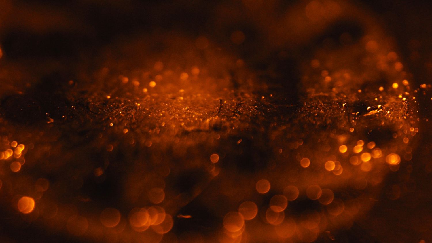 Glowing orange bokeh lights create a magical abstract background with blurred circular patterns.