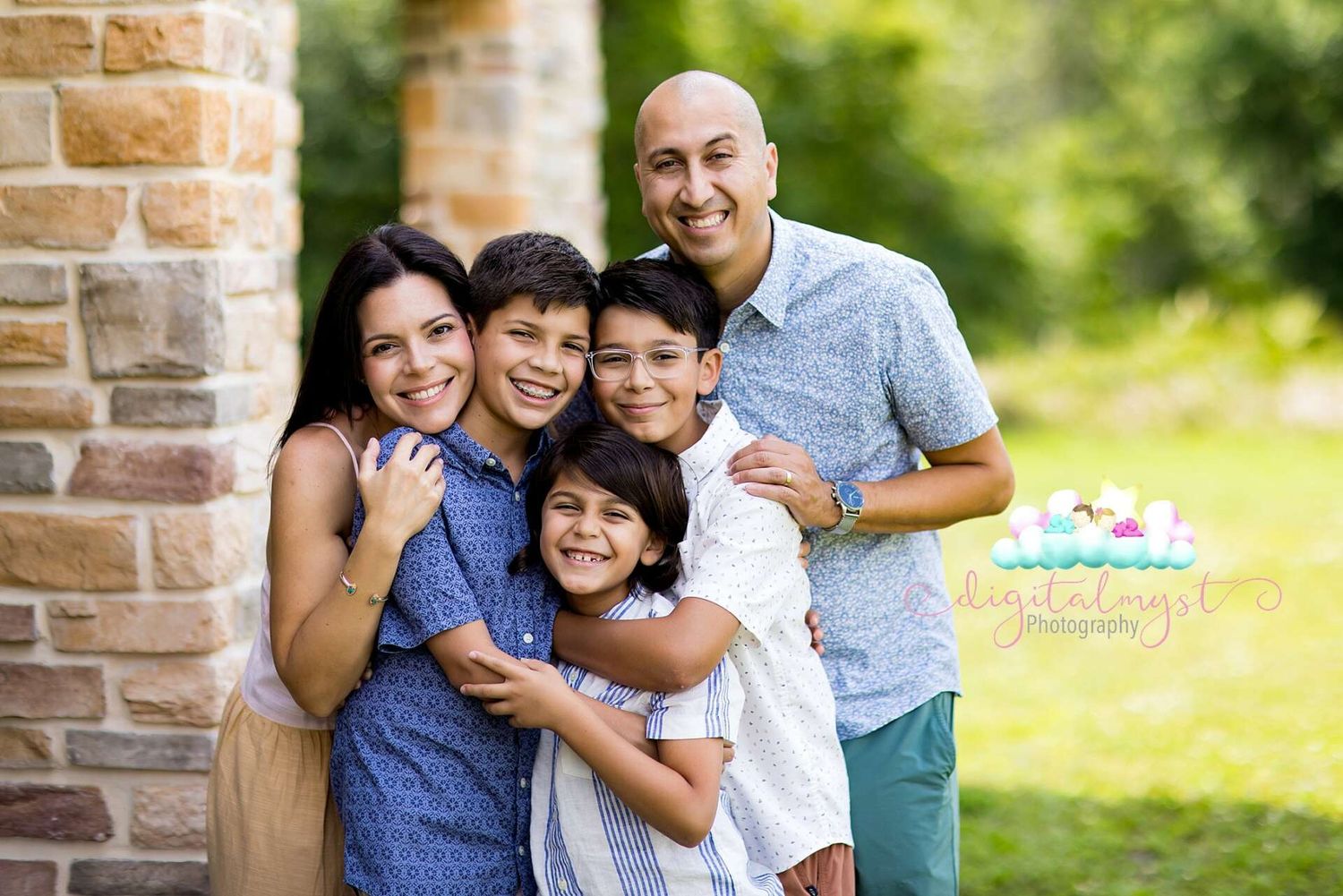 Happy family captures a warm moment together outdoors by stone pillars on sunny day.