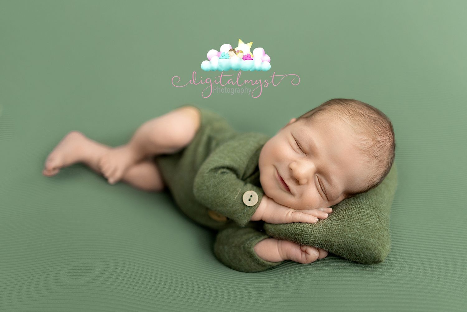 A sleeping newborn baby wearing a cozy green knit romper lies curled up on a green background.