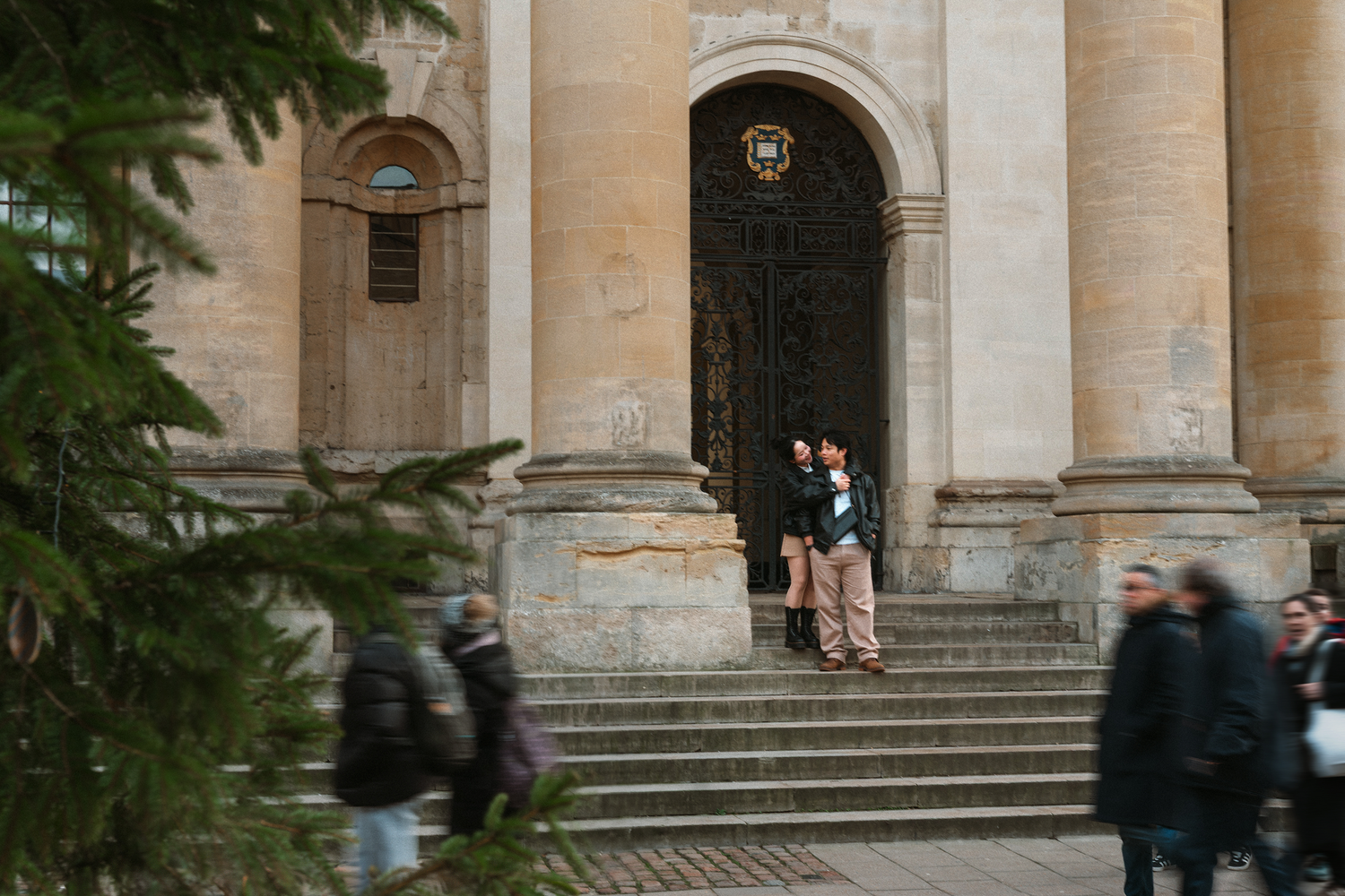 People gather on the steps of a grand stone building with classical architecture.