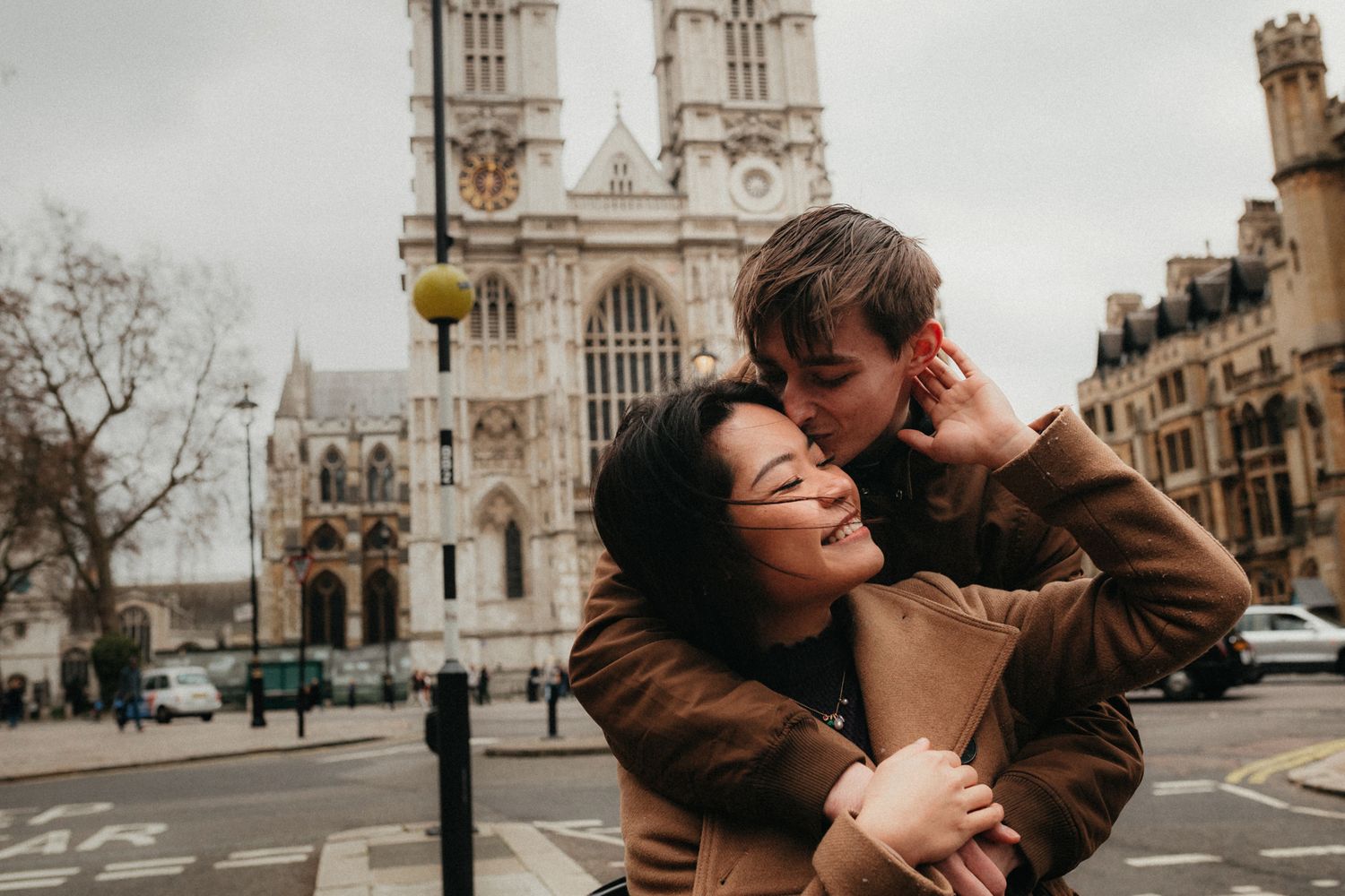 Romantic couple embraces near historic London architecture and streets.