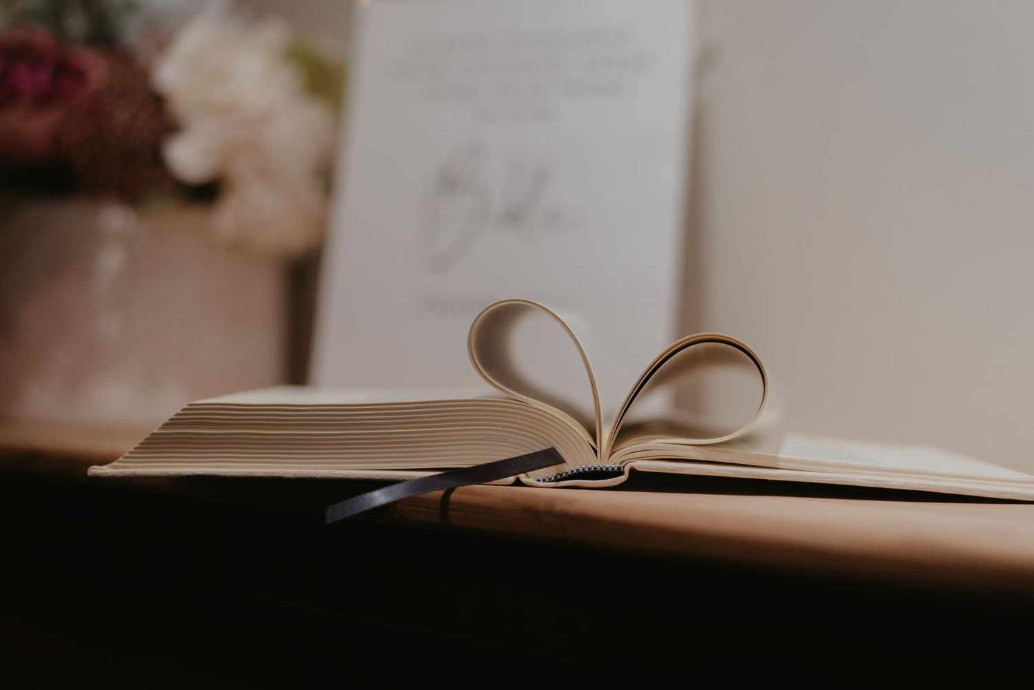 An open hardcover Bible with pages fanned out, photographed with shallow depth of field in warm lighting.