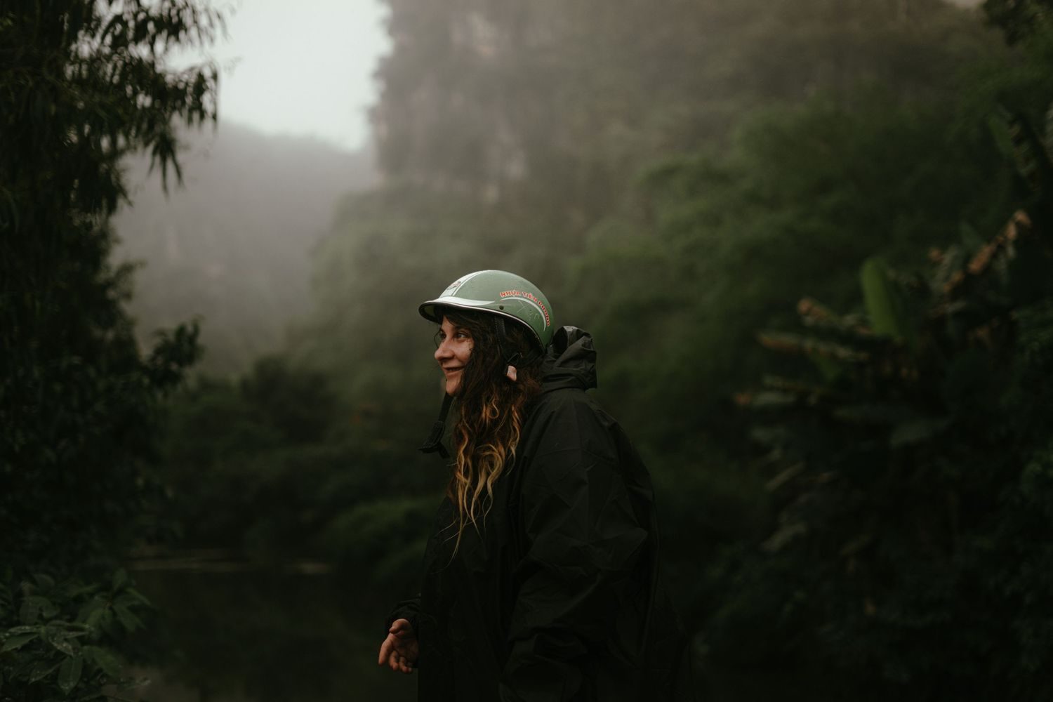 Hiker in black jacket and helmet exploring misty mountain terrain.