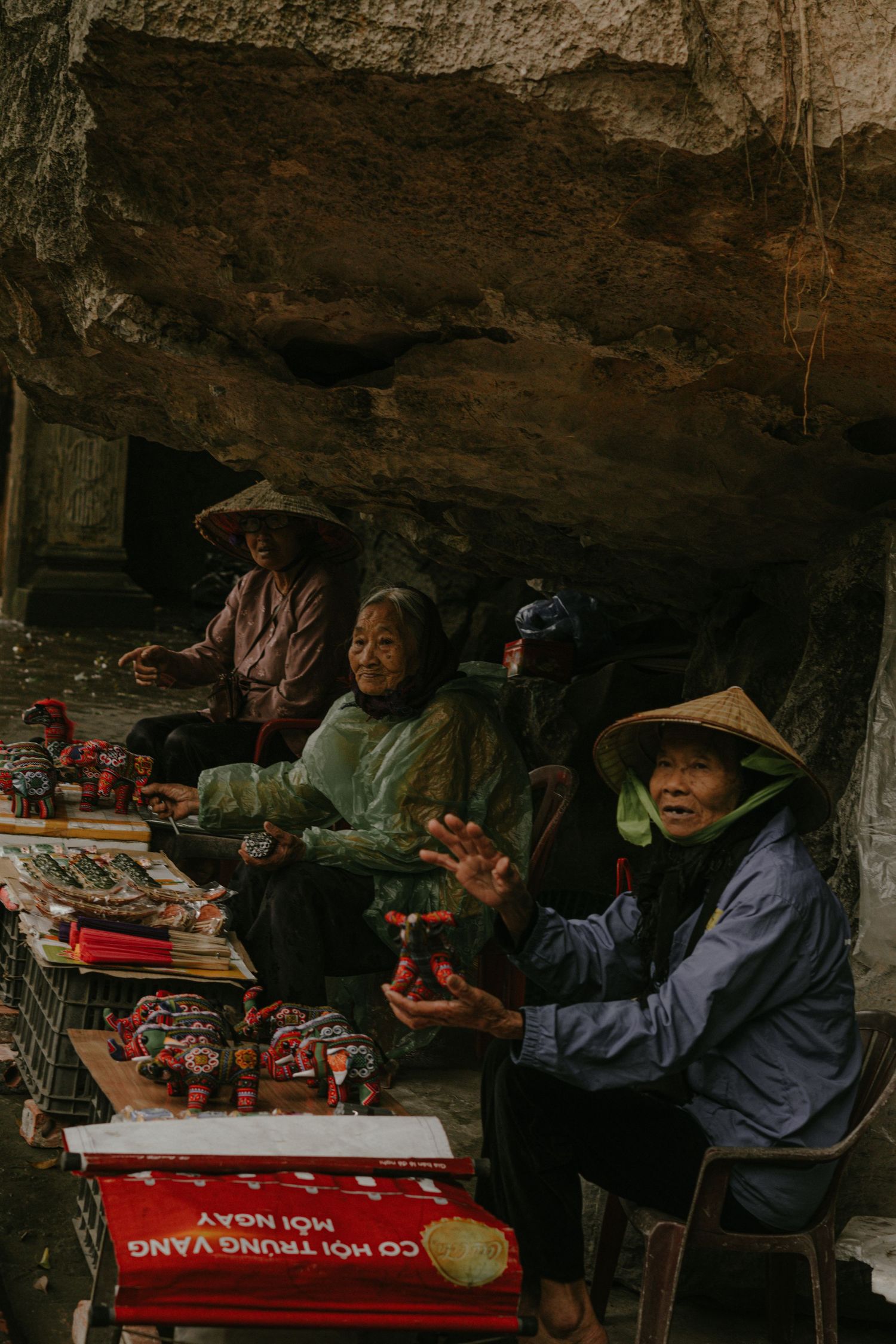 Local vendors display their wares under a rocky cave overhang in rural Asia.