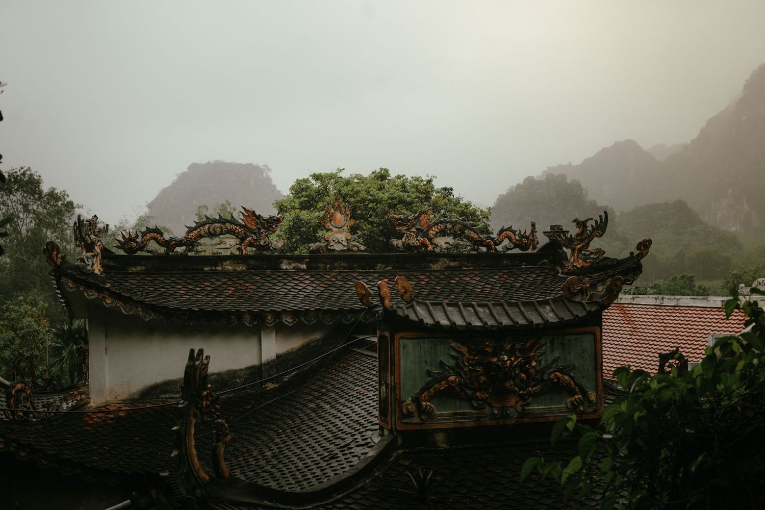 Traditional Chinese temple roof with ornate details against misty mountain backdrop.