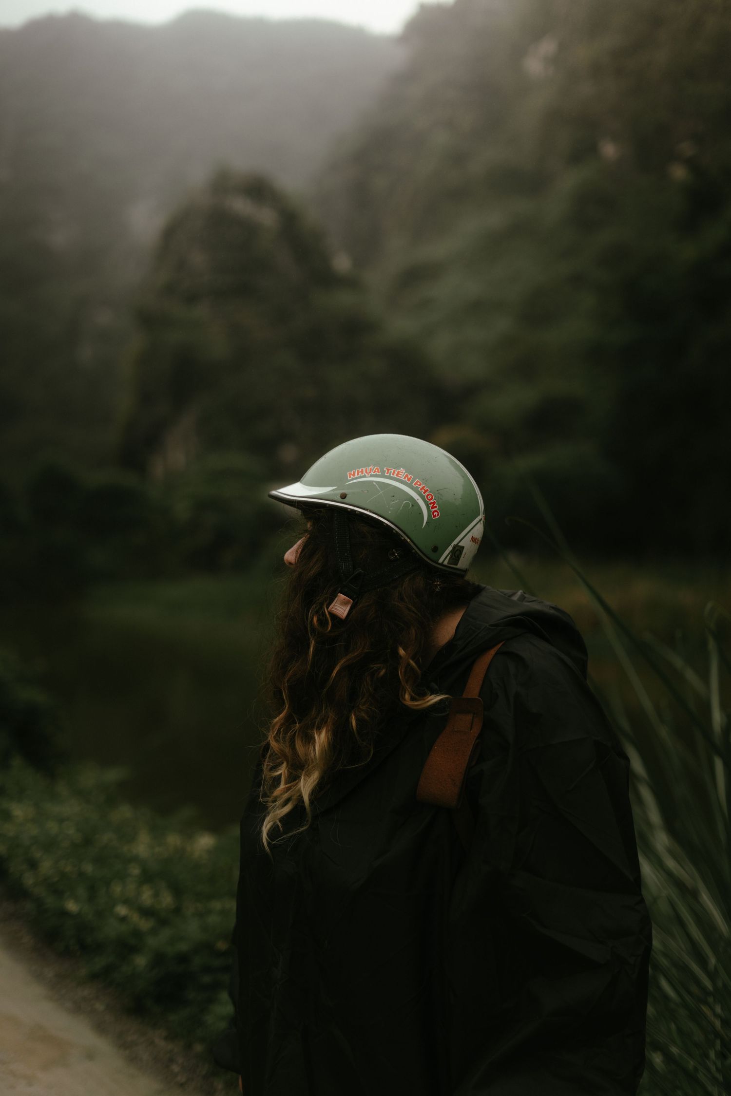 Adventure seeker wearing a green helmet against misty mountain backdrop.
