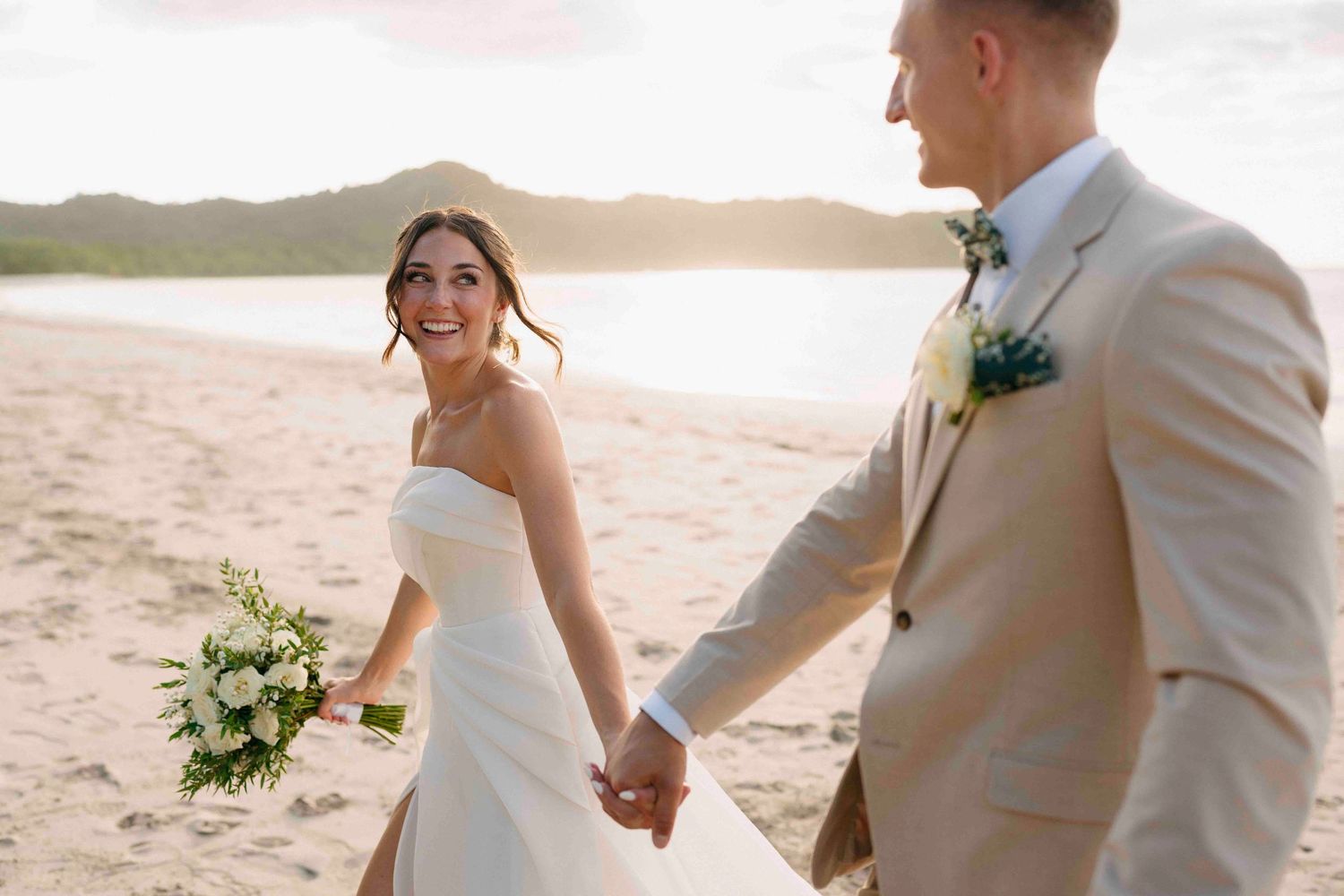 a bride and groom walking through the ocean enjoying the white sand of Playa conchal guanacaste