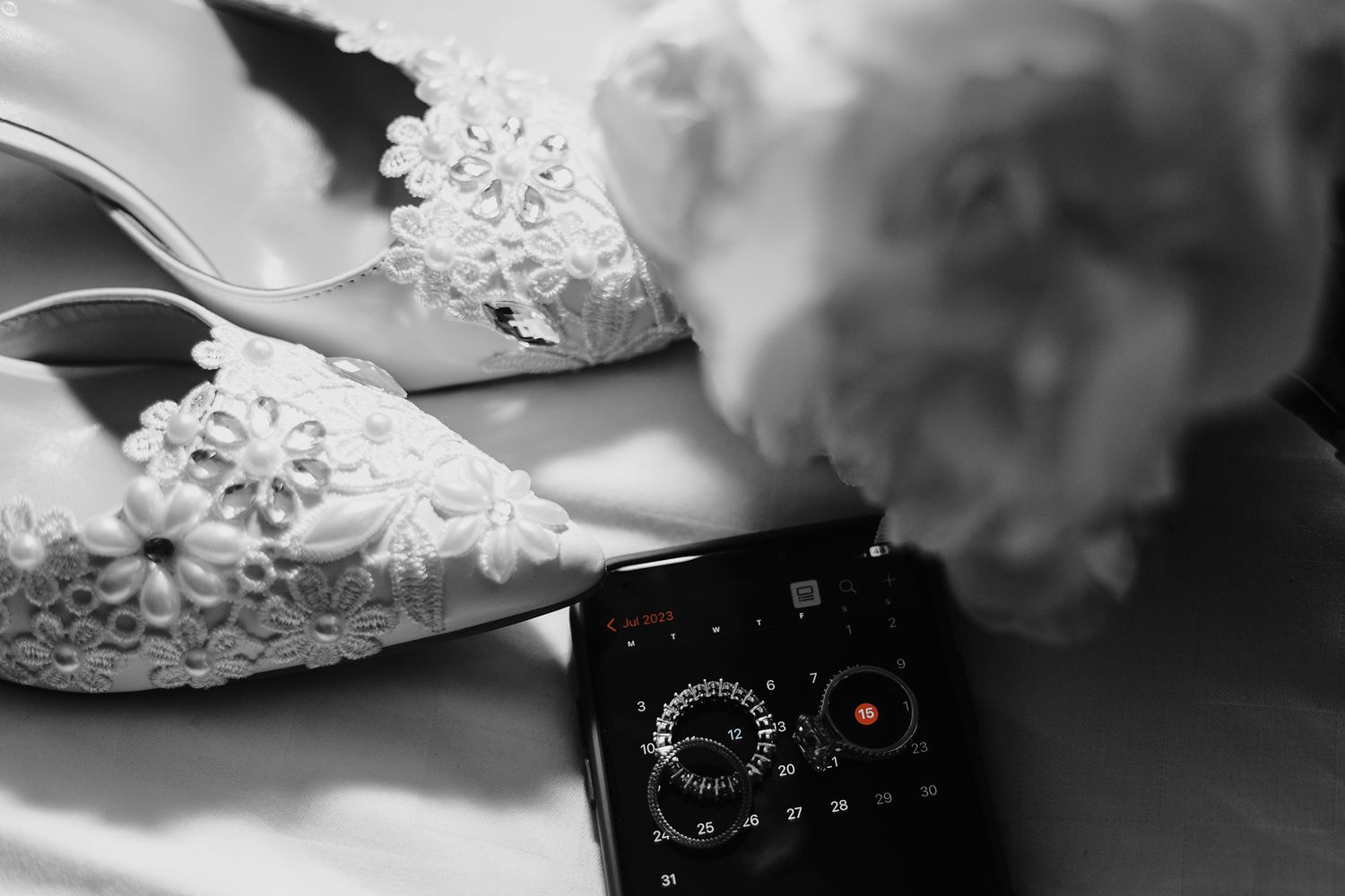 A detailed image of a brides wedding shoe, bouquet and wedding rings on an iphone