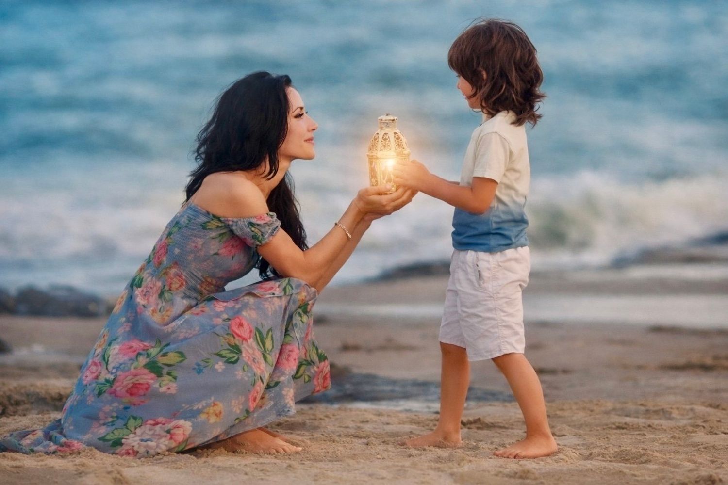 Woman in floral dress and child sharing a glowing lantern on a sandy beach at sunset.