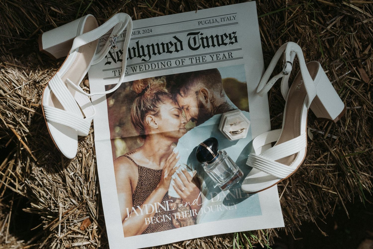 Wedding rings and a newspaper clipping rest on scattered white papers in natural light.