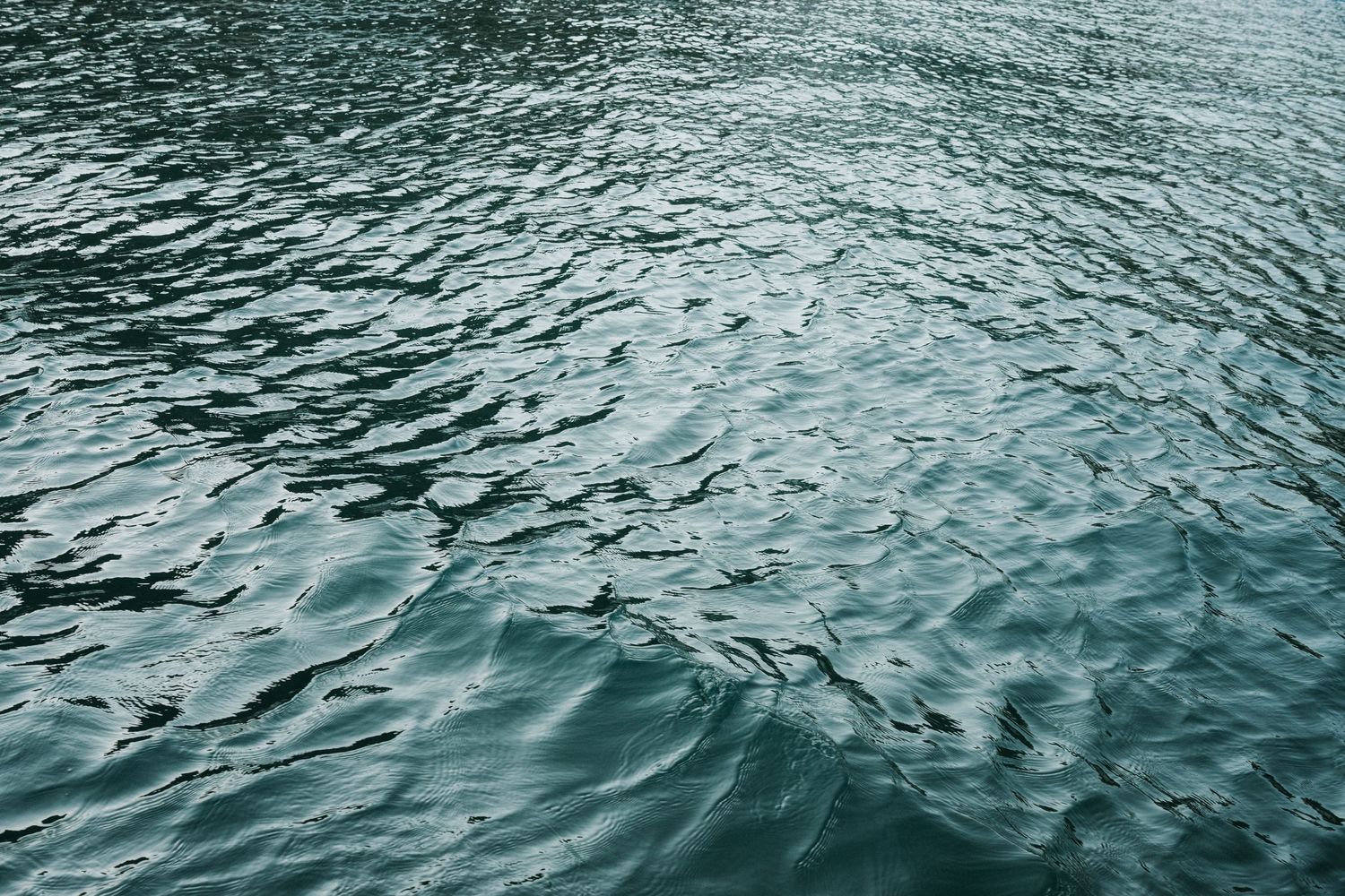 Rippling turquoise ocean water surface creates abstract patterns and textures in sunlight.