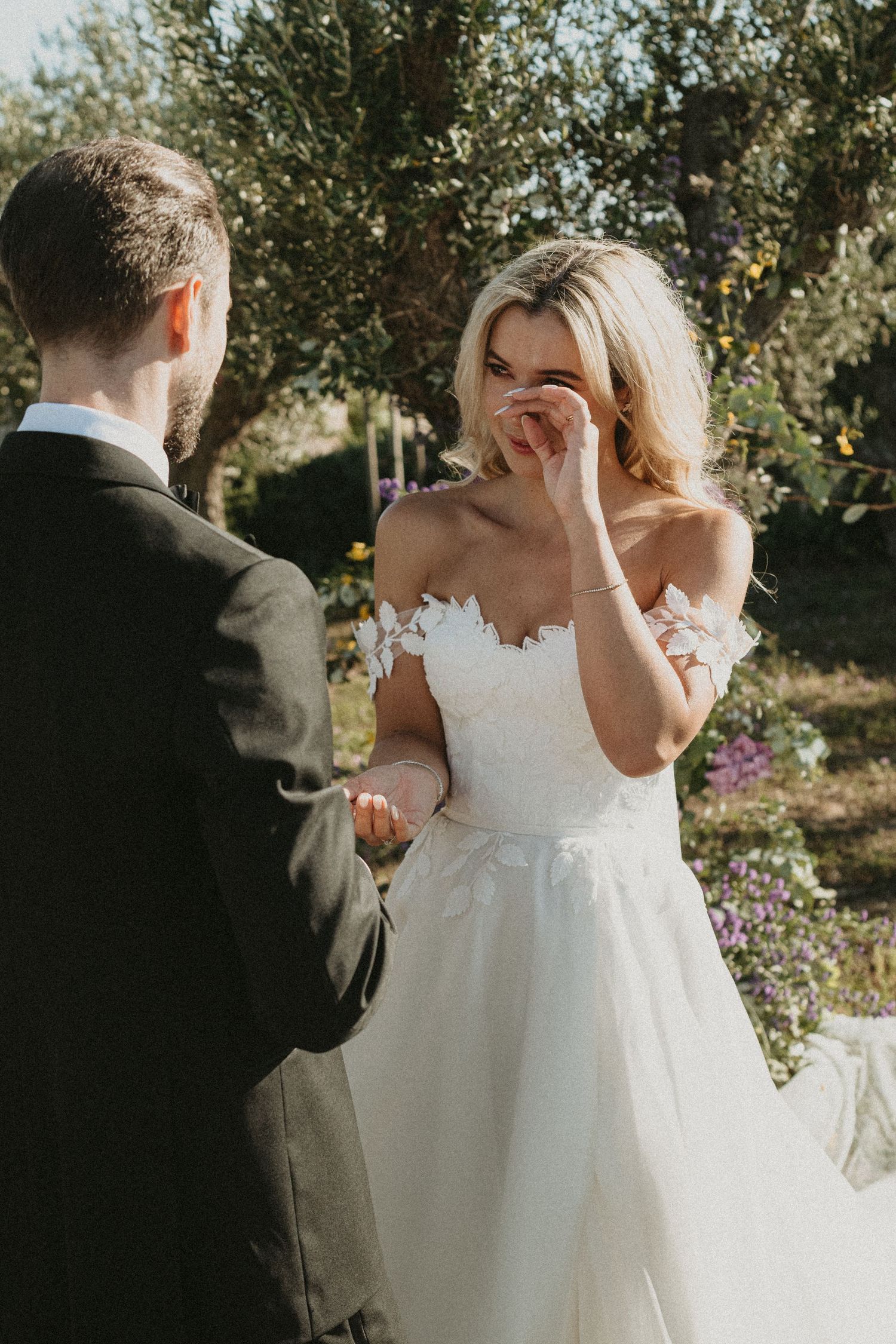 Emotional first look moment between bride and groom in an outdoor garden setting with soft natural lighting.