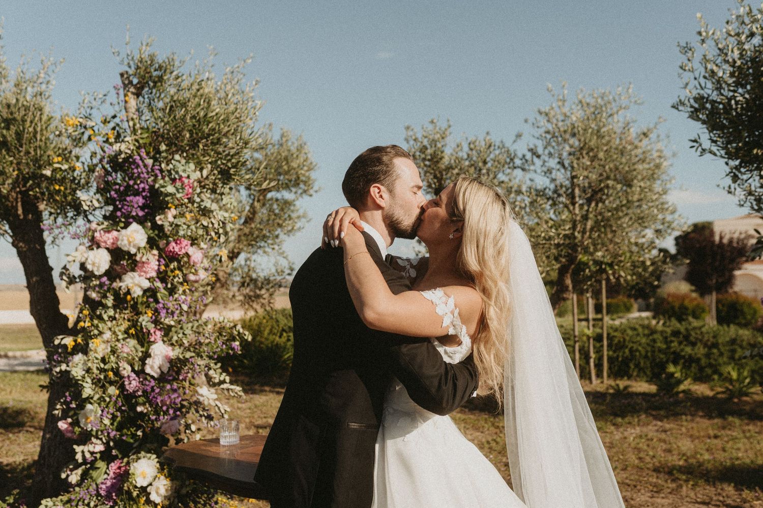 Romantic wedding couple embraces in an olive grove during golden hour sunset.
