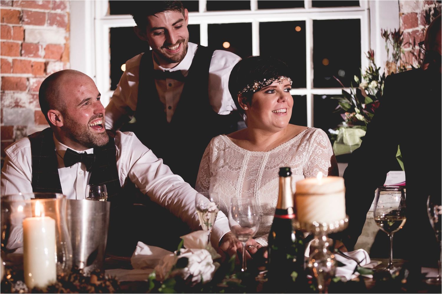 People enjoying a joyful celebration at an elegant dinner party with candles and drinks on the table.