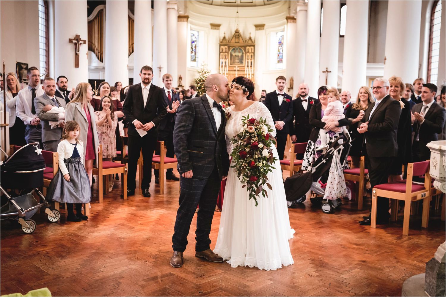 Two wedding figures celebrate at their ceremony in a grand church sanctuary with guests watching and applauding.