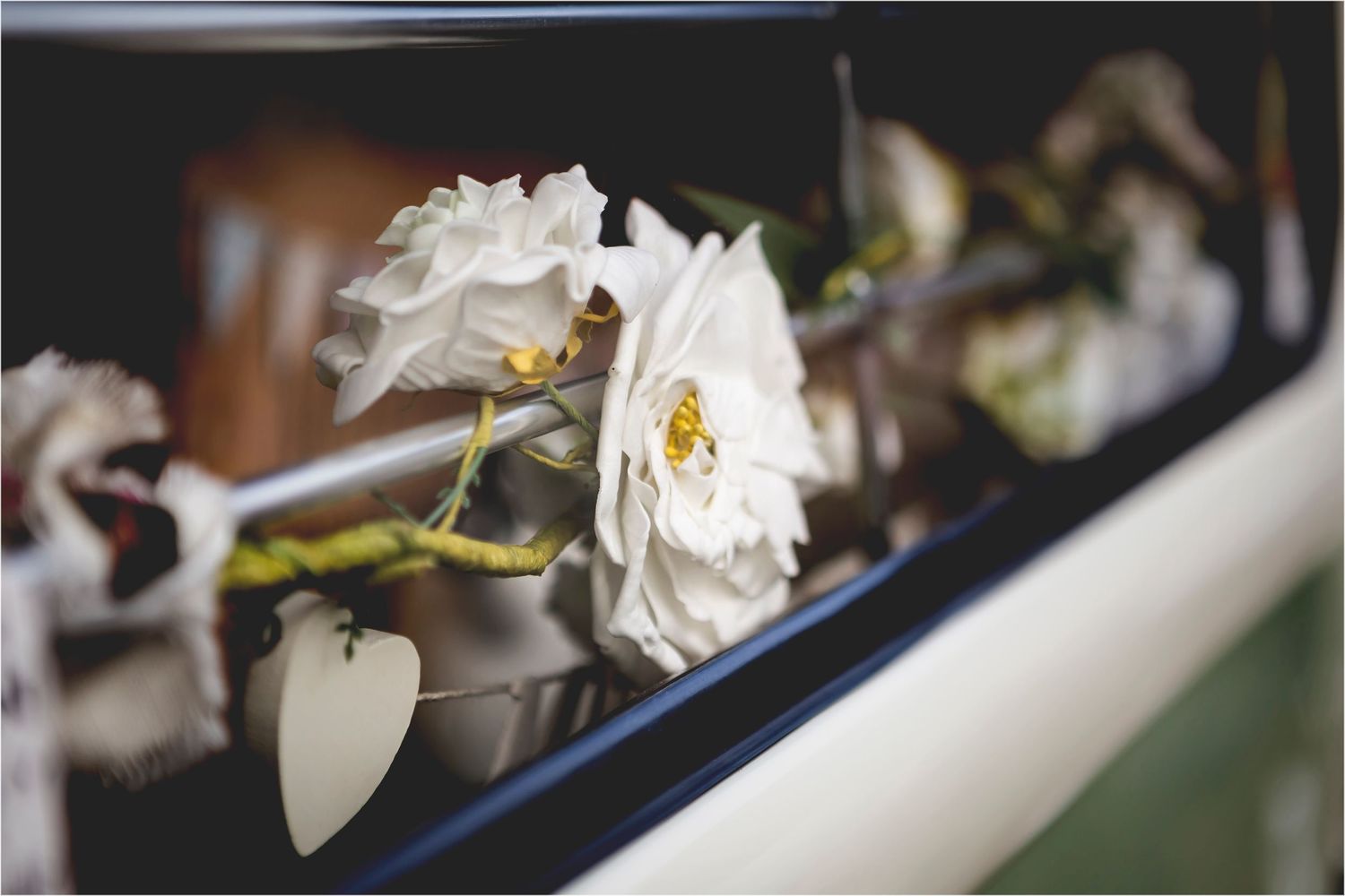 White roses and a small heart decoration adorn the edge of what appears to be a dark vehicle window.
