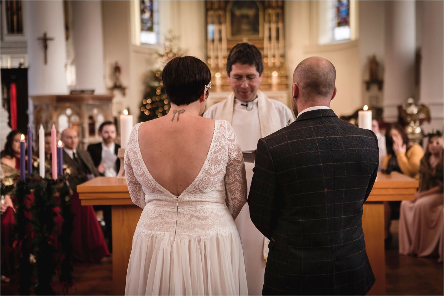 A wedding ceremony takes place inside a traditional church with the couple and officiant at the altar.