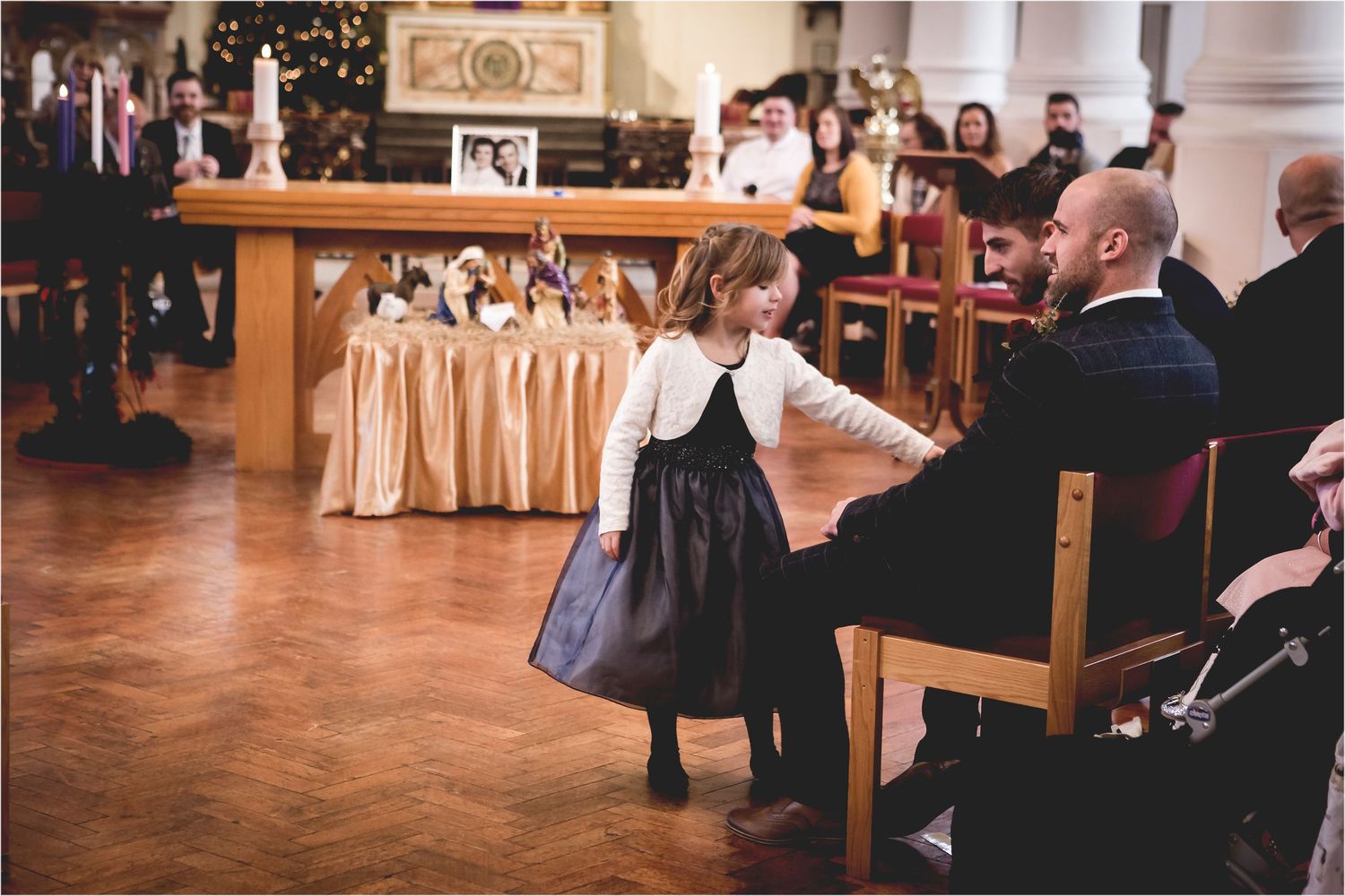 Wedding guests dance and mingle in a rustic wooden reception hall decorated with string lights and warm ambiance.