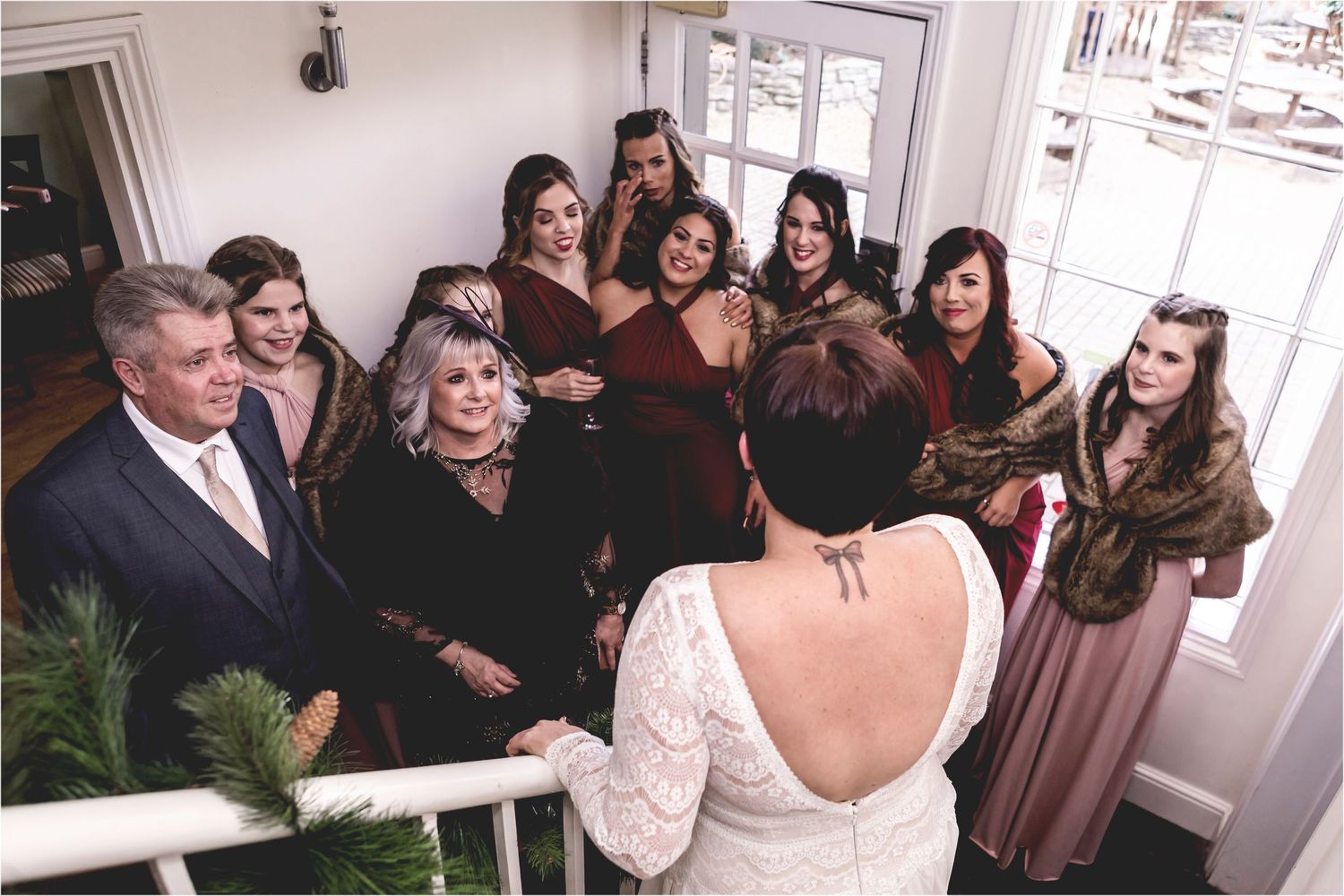 Group of attendees gather around on a porch during a celebratory event while viewing the back of a white lace dress.