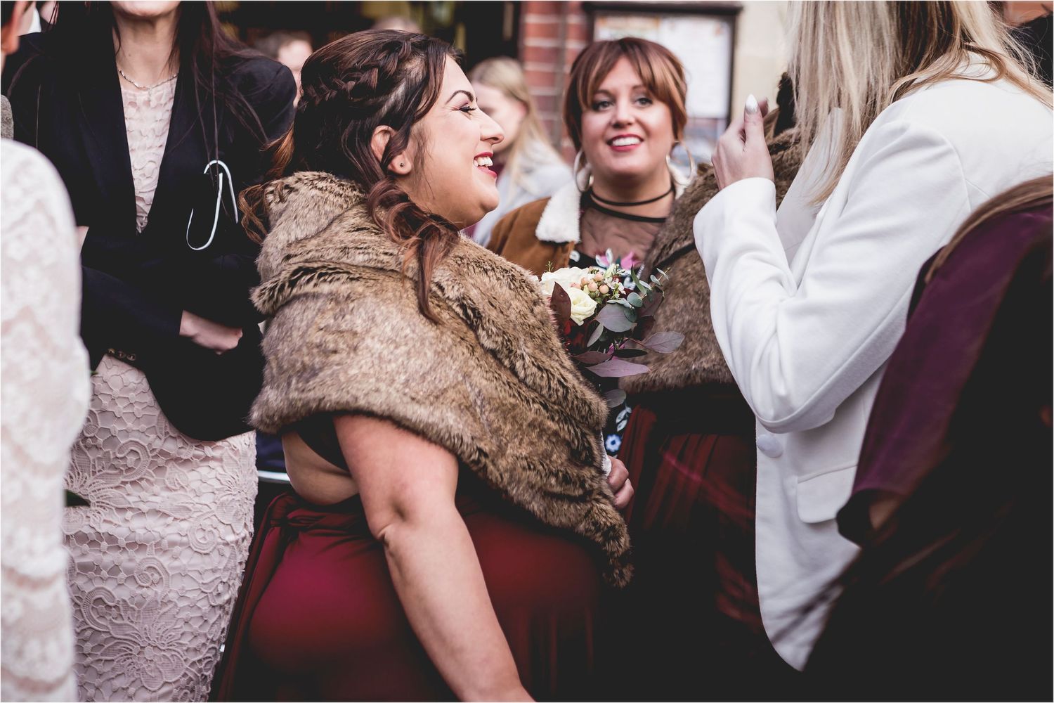 Candid moment from a formal event showing people laughing and socializing while dressed in elegant winter attire.