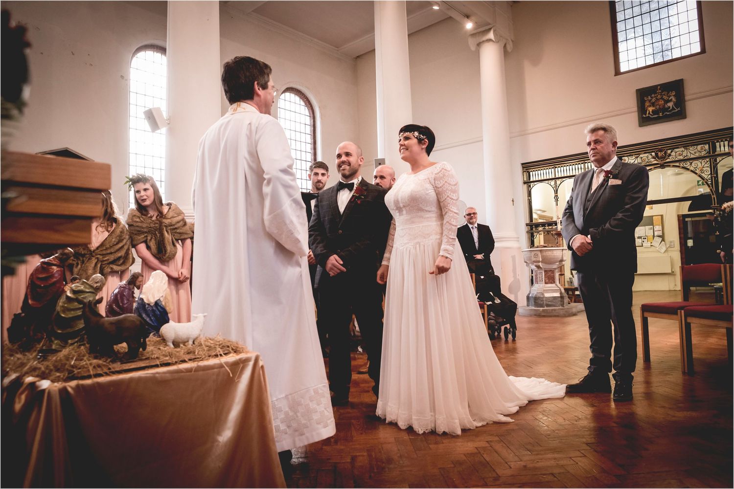 A wedding ceremony takes place in a traditional church with elegant decor and natural light streaming through windows.