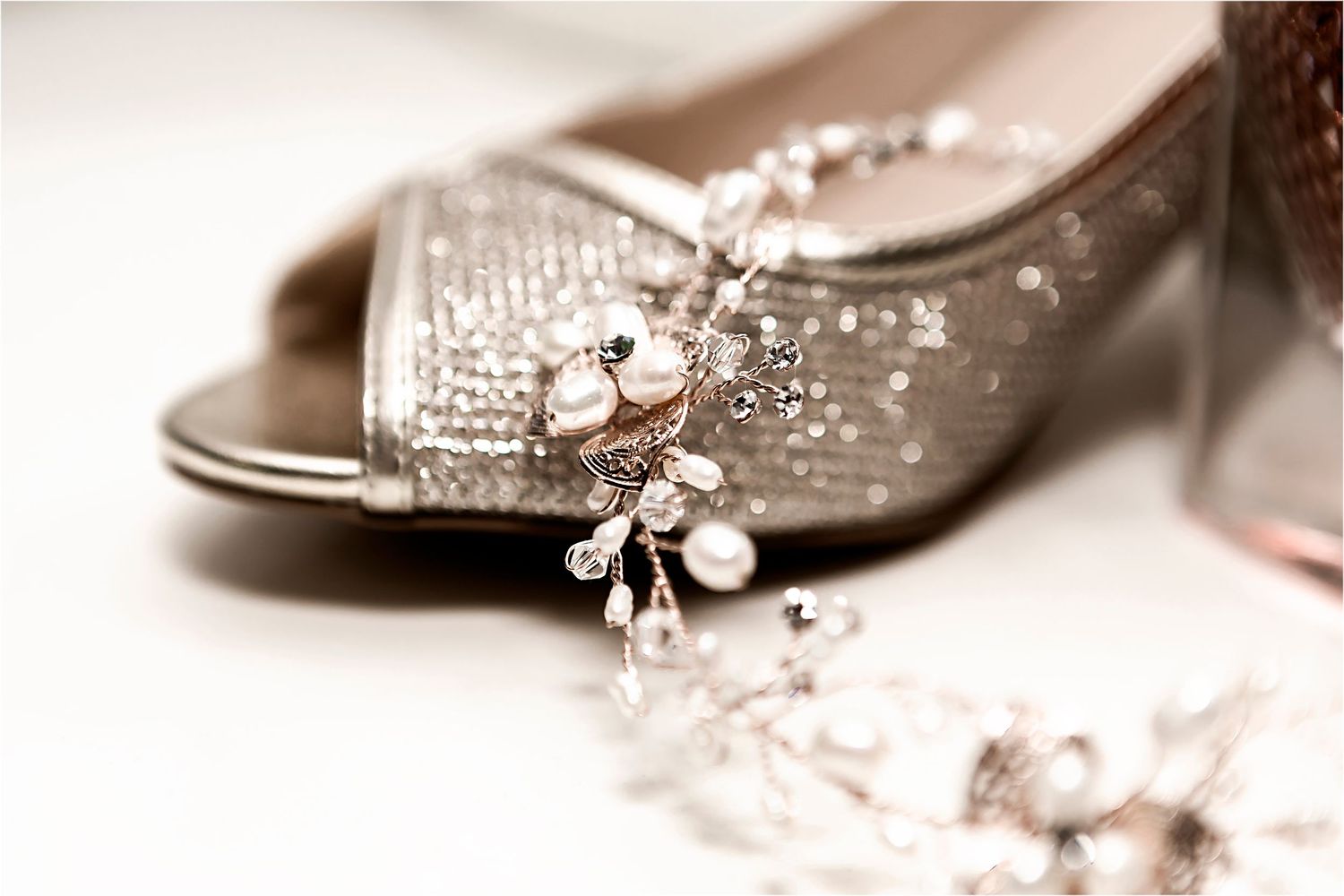 Elegant bridal shoe with sparkling rhinestone details and pearl decorations in soft sepia tones.