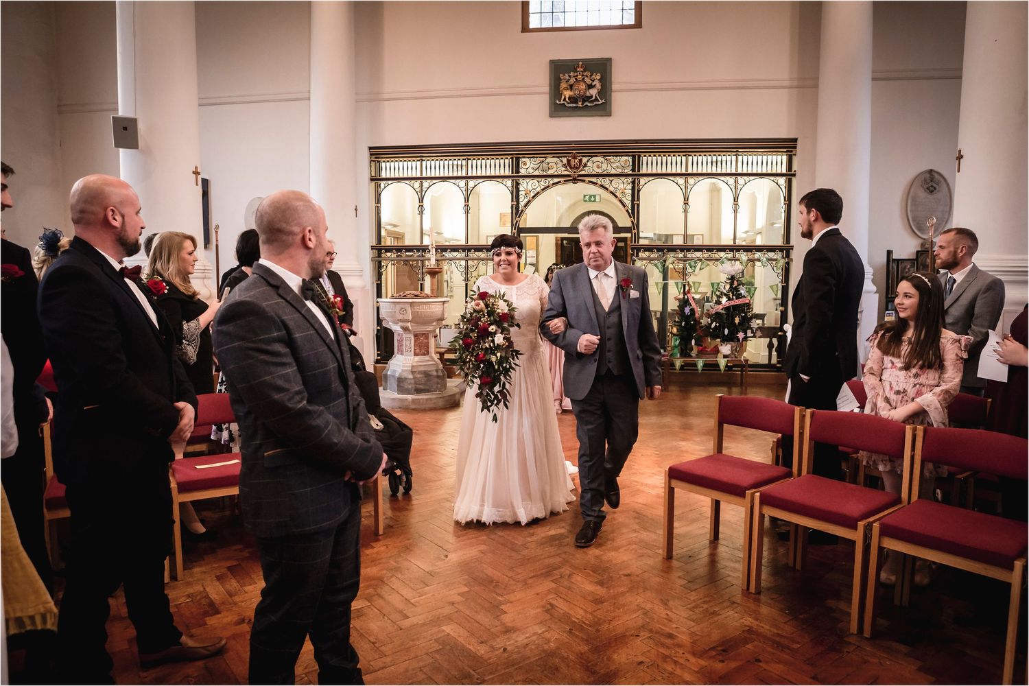 A wedding ceremony taking place inside a church with guests watching as a couple walks down the aisle.
