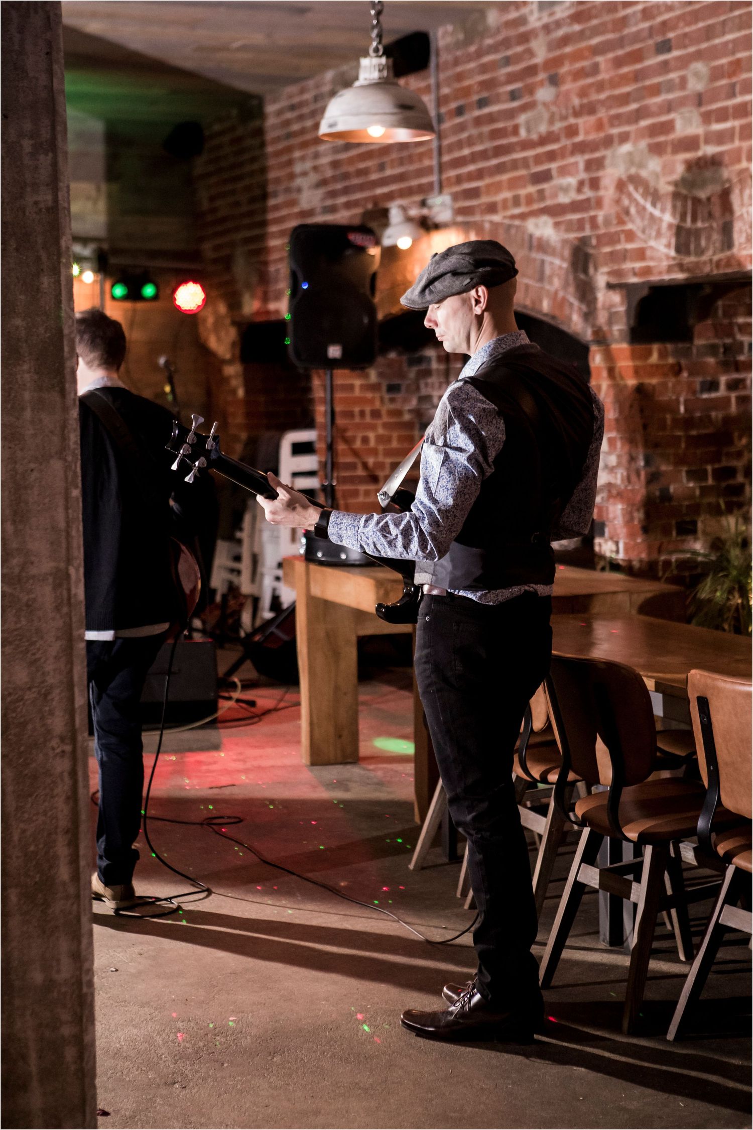 Musicians perform in a rustic brick-walled venue with vintage lighting and industrial decor.
