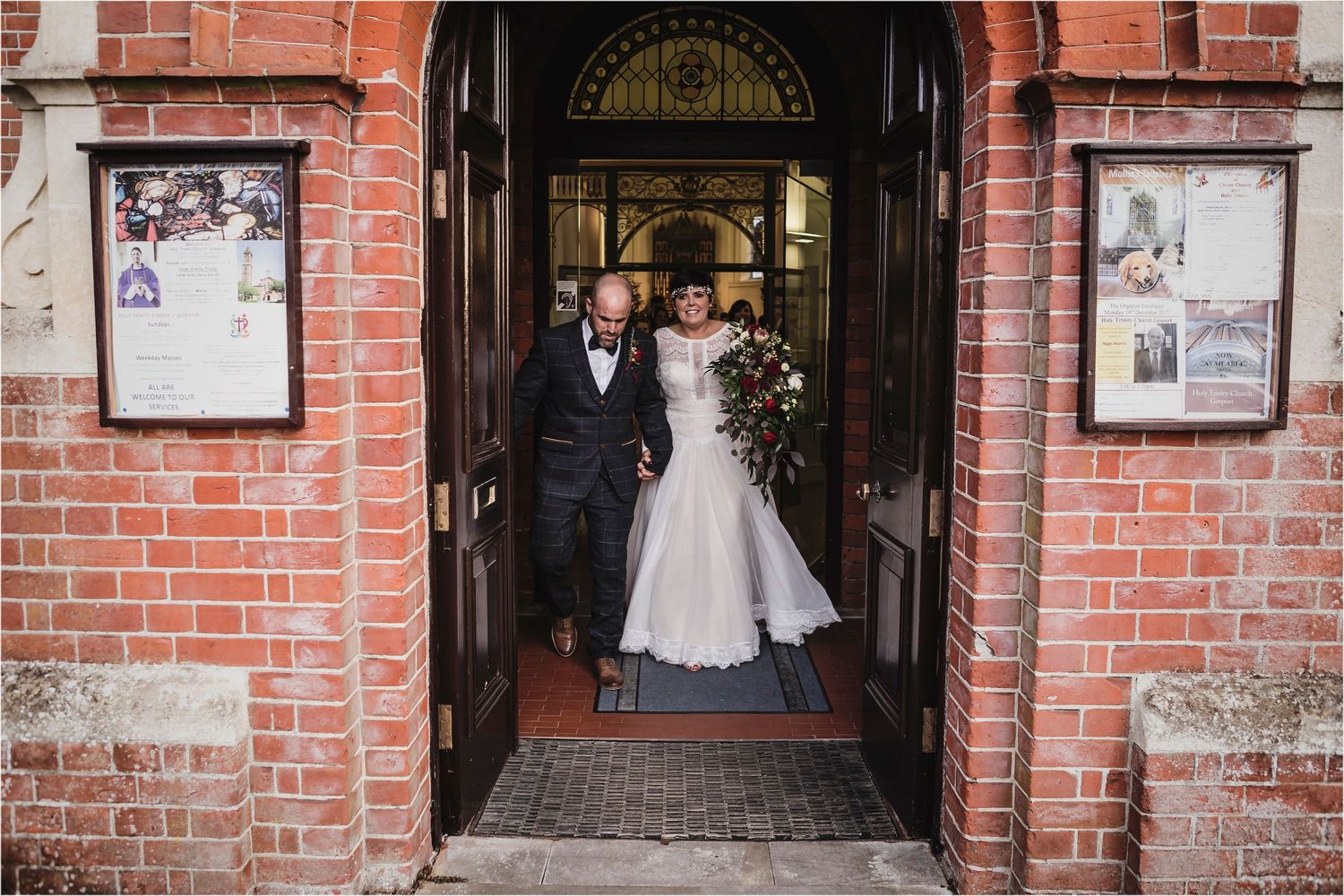 Couple standing in arched brick doorway entrance with poster boards on each side of historic building entrance.