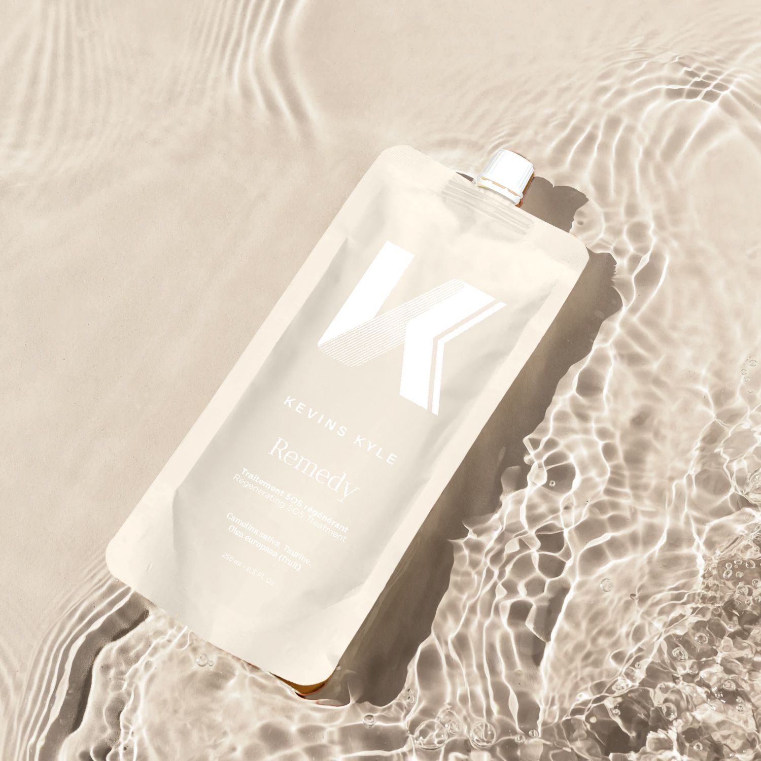 Keune Vital Remedy hair treatment pouch floating on shimmering water with a soft, neutral aesthetic.
