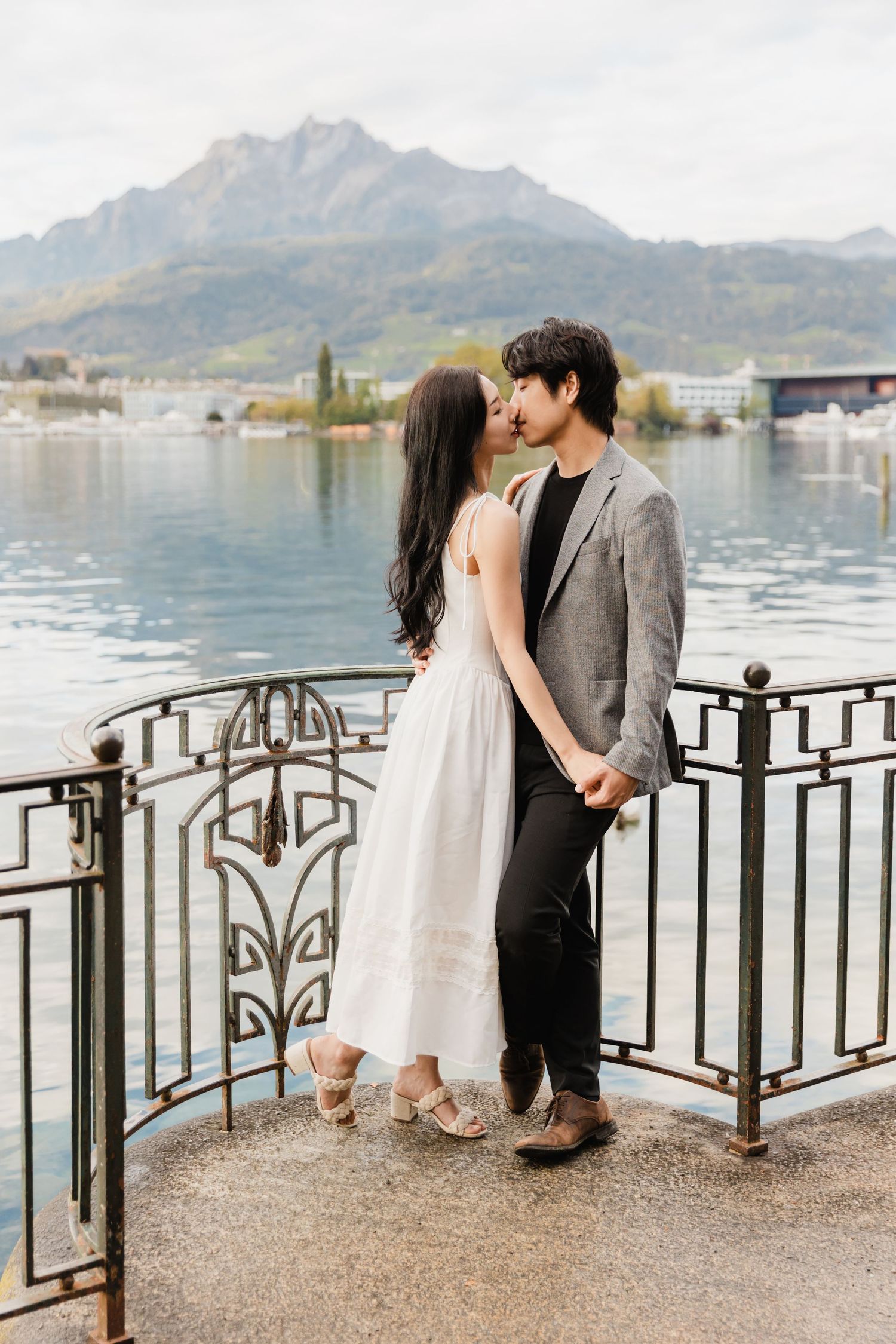 An asian couple kissing by a river with a mountain in the background in the lake Lucerne