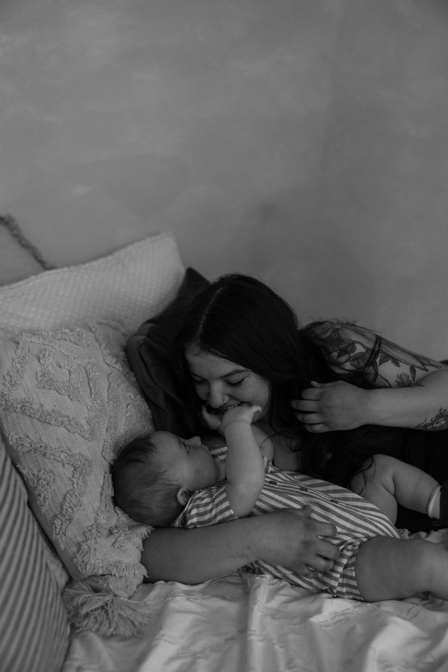 Black and white photo of a mother lovingly gazing at her newborn baby while lying in bed.