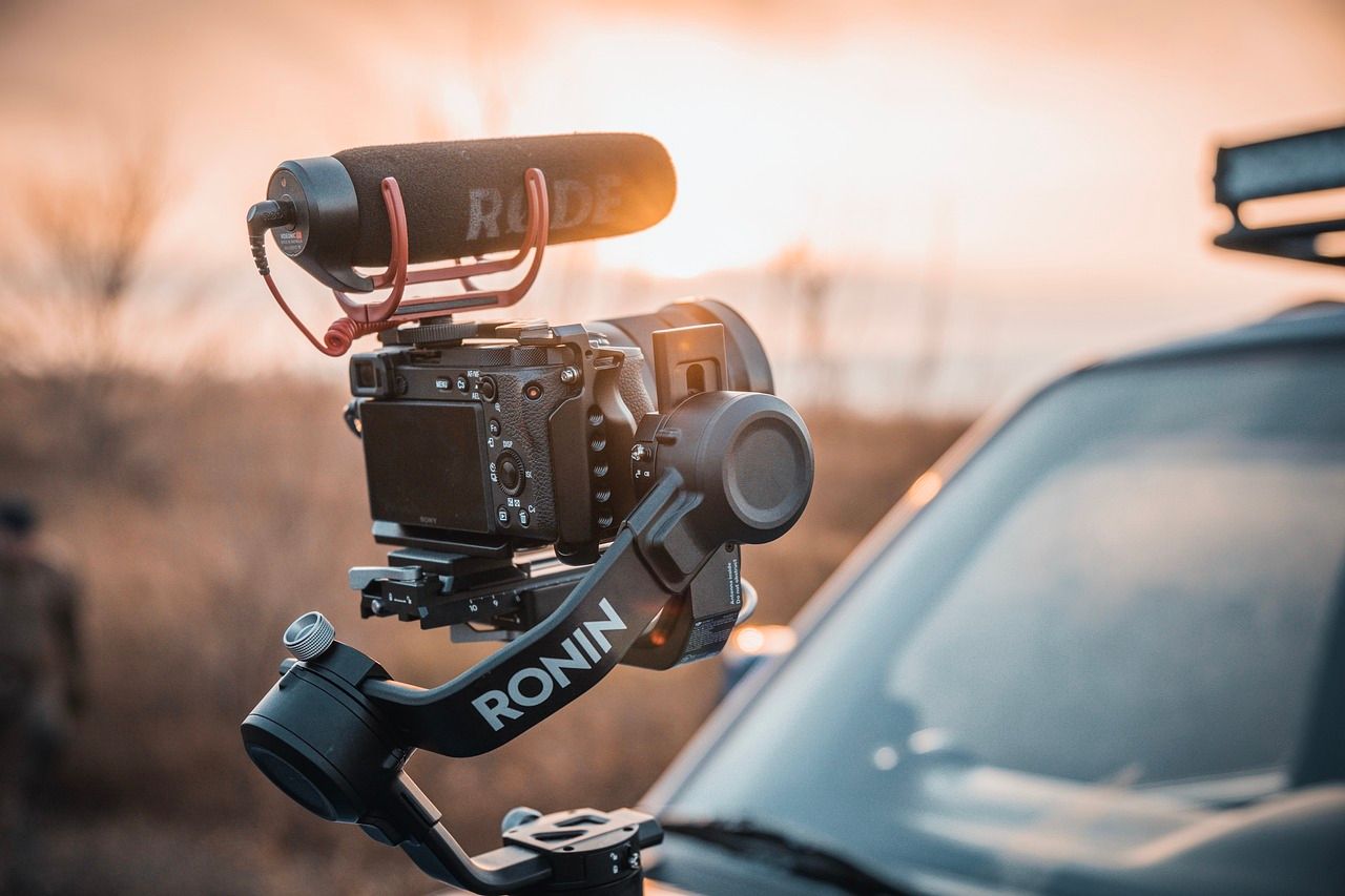 DJI Ronin camera gimbal stabilizer with a DSLR and Rode microphone at sunset.