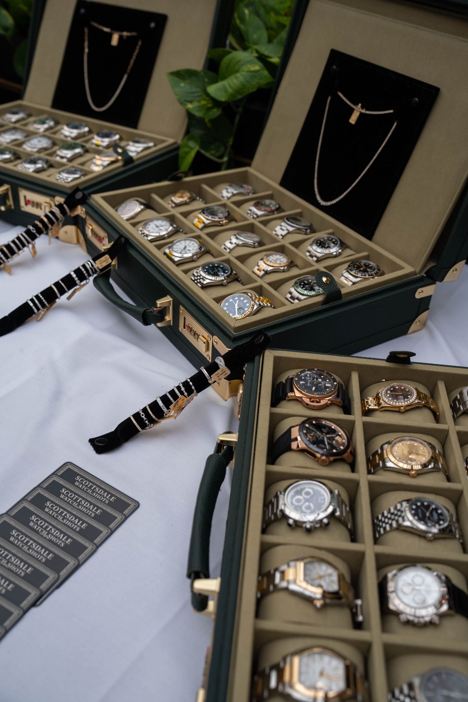 Luxury watch display cases filled with Rolex and designer timepieces arranged on a white table at an upscale jewelry showcase.