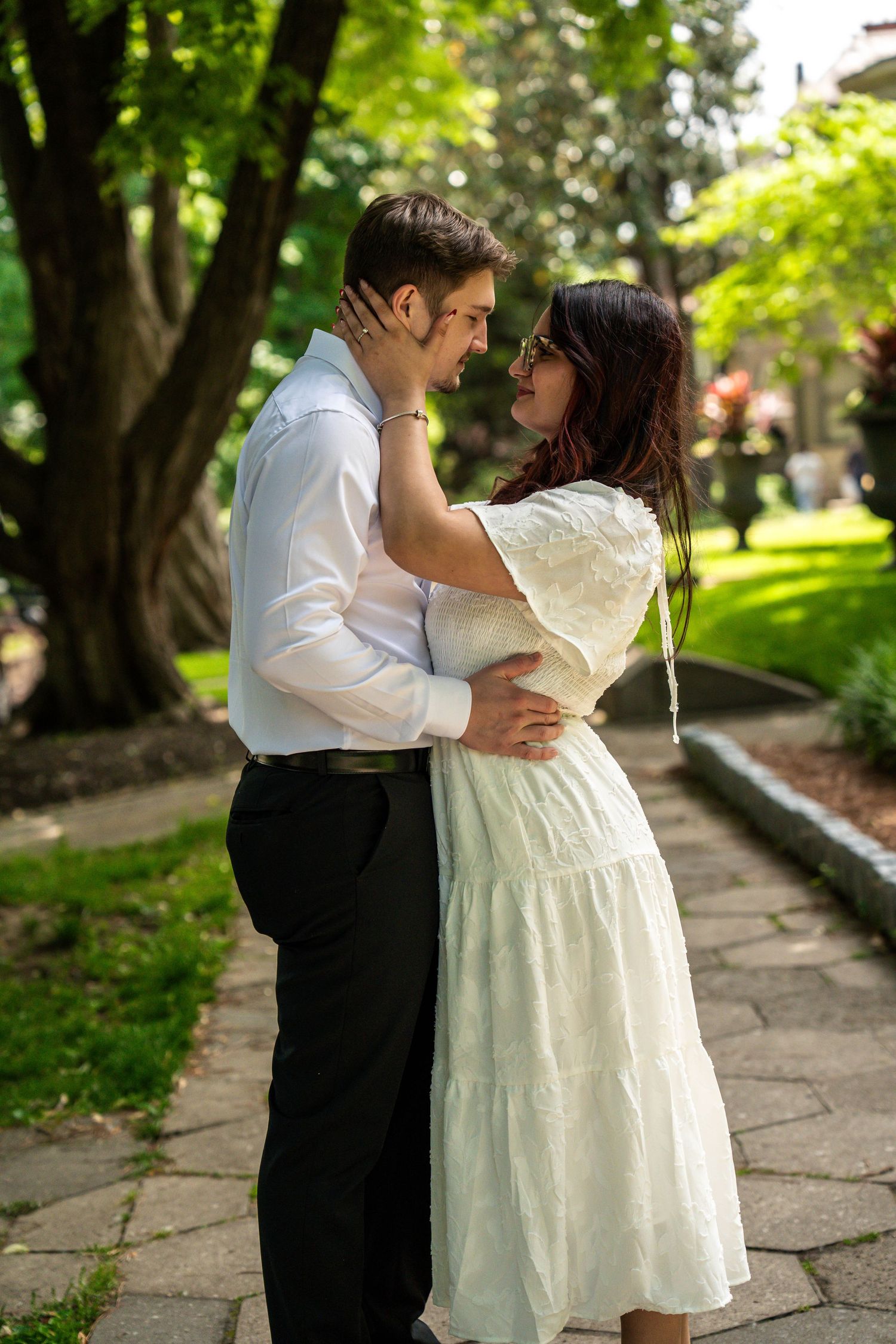 Couple embracing and almost kissing in lush green park setting.