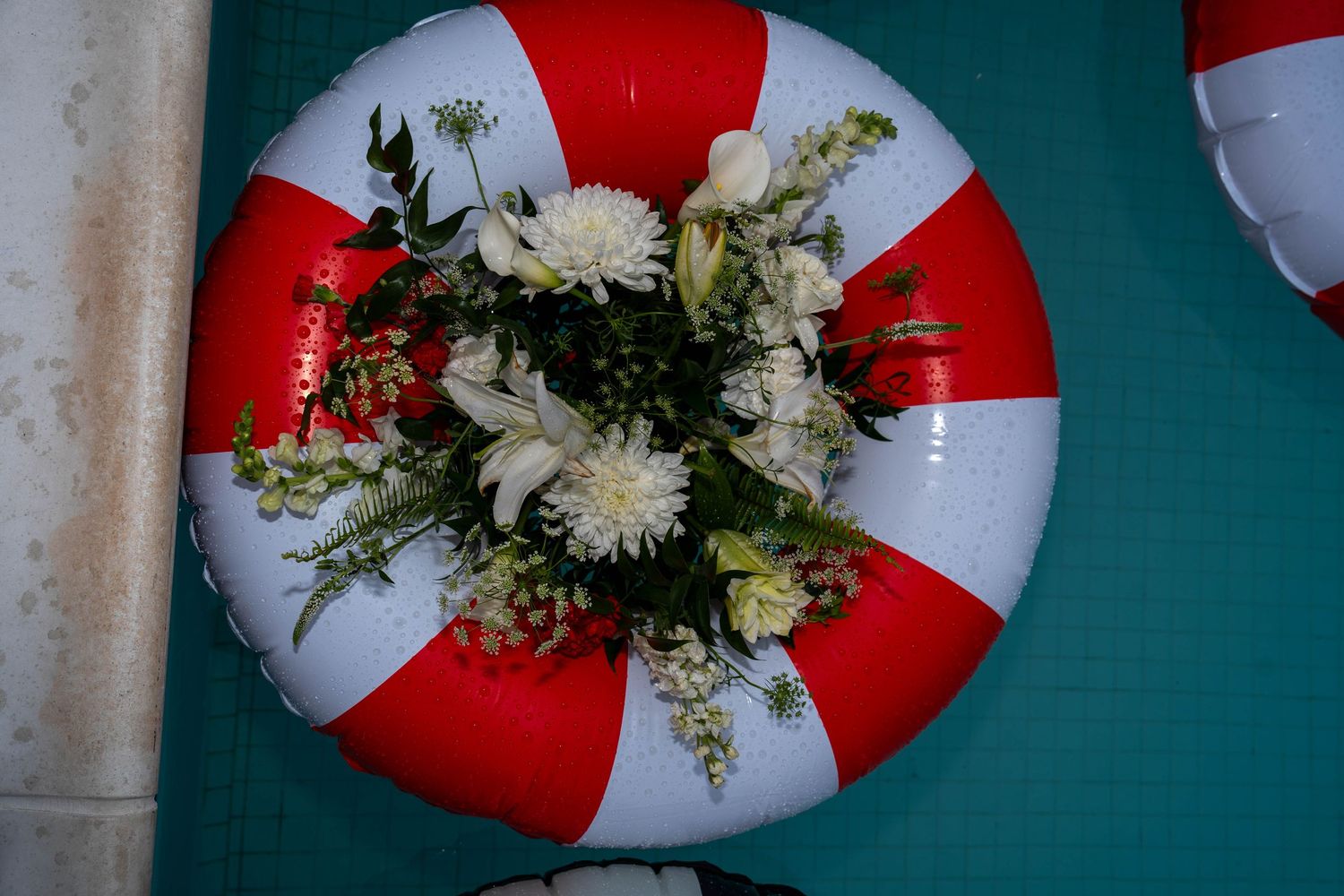 Red and white life preserver ring used as a floral centerpiece with white chrysanthemums and greenery.