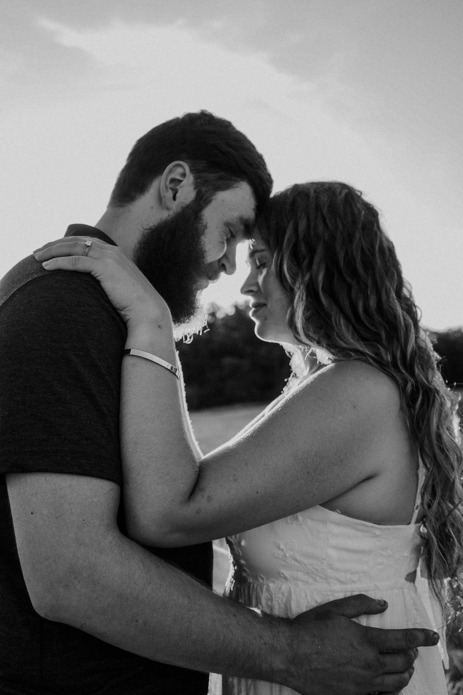 Black and white romantic portrait of bearded man and woman embracing forehead to forehead.