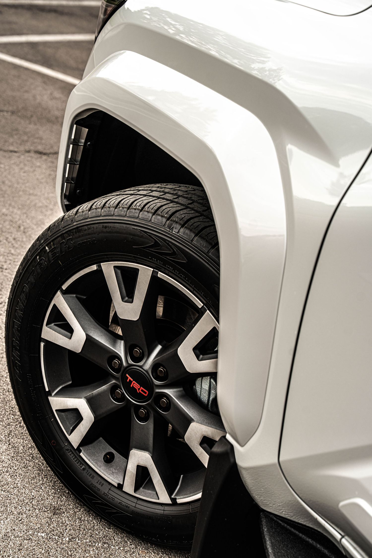 Close-up of a white Toyota TRD SUV showcasing a black and silver alloy wheel with TRD logo and wide-body fender flare.