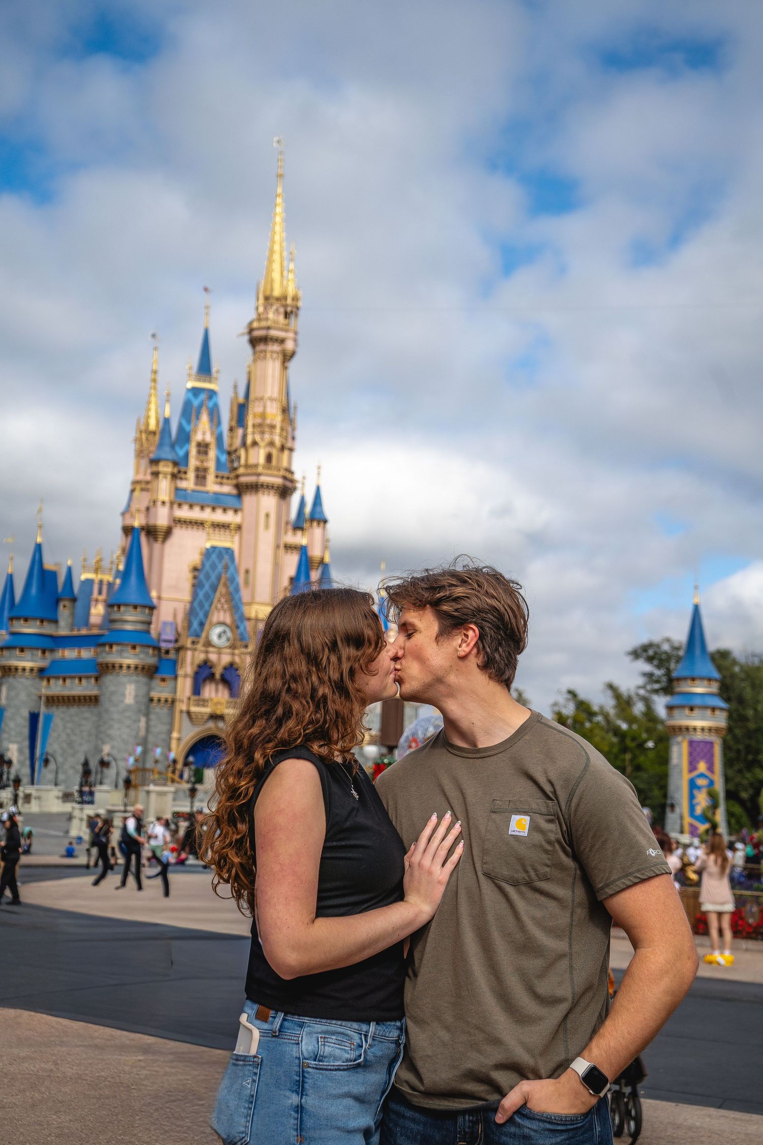 Romantic couple sharing a kiss in front of Cinderella Castle at Walt Disney World.