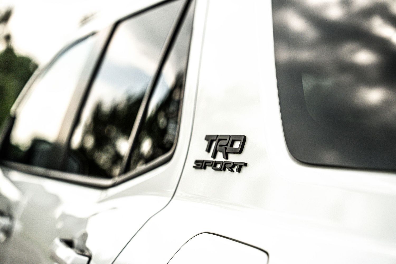 Close-up of a TRD Sport badge emblem on a white Toyota vehicle exterior.