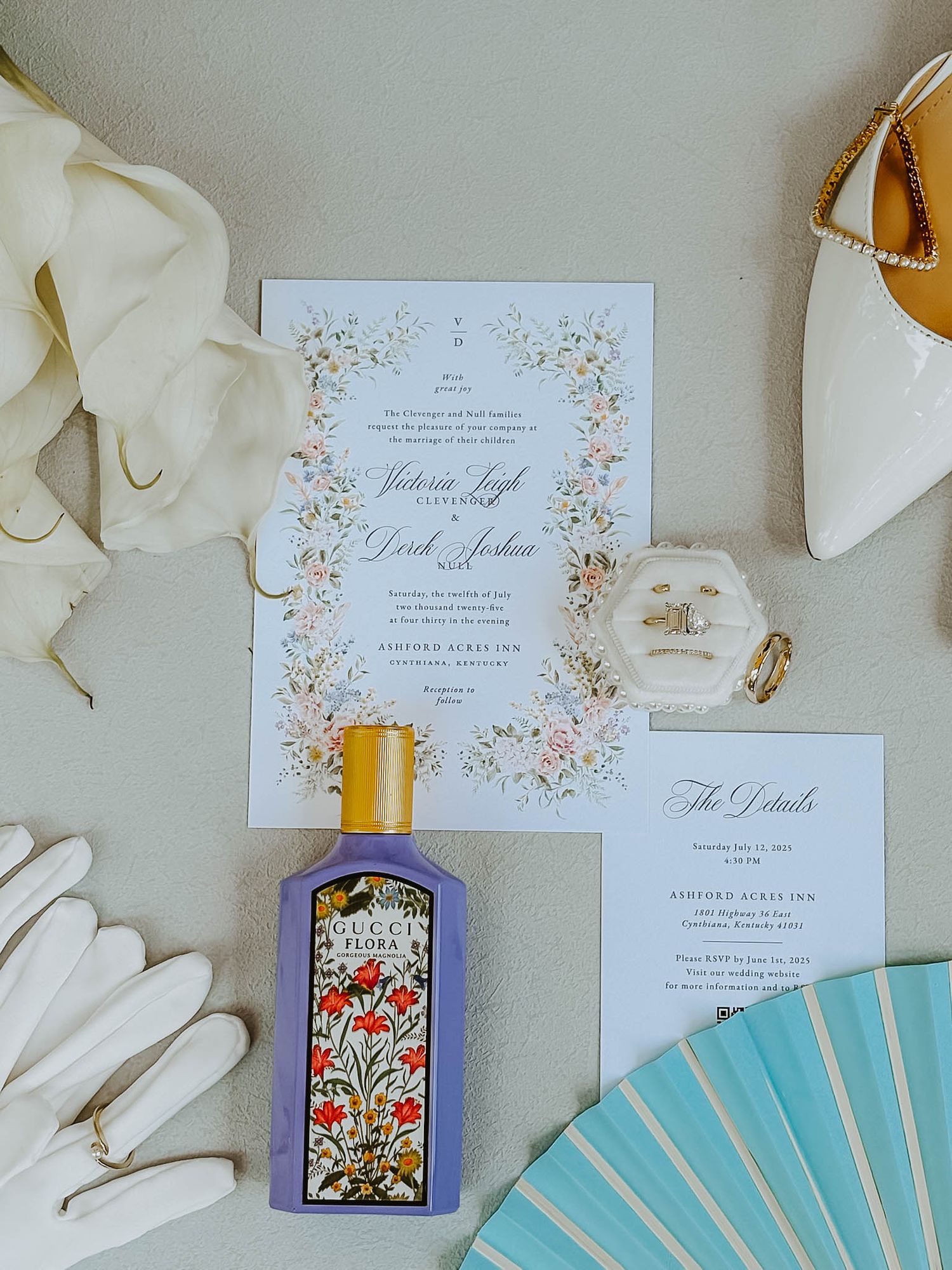 Wedding invitation flatlay with Gucci Flora perfume, white gloves, floral stationery, and bridal accessories.