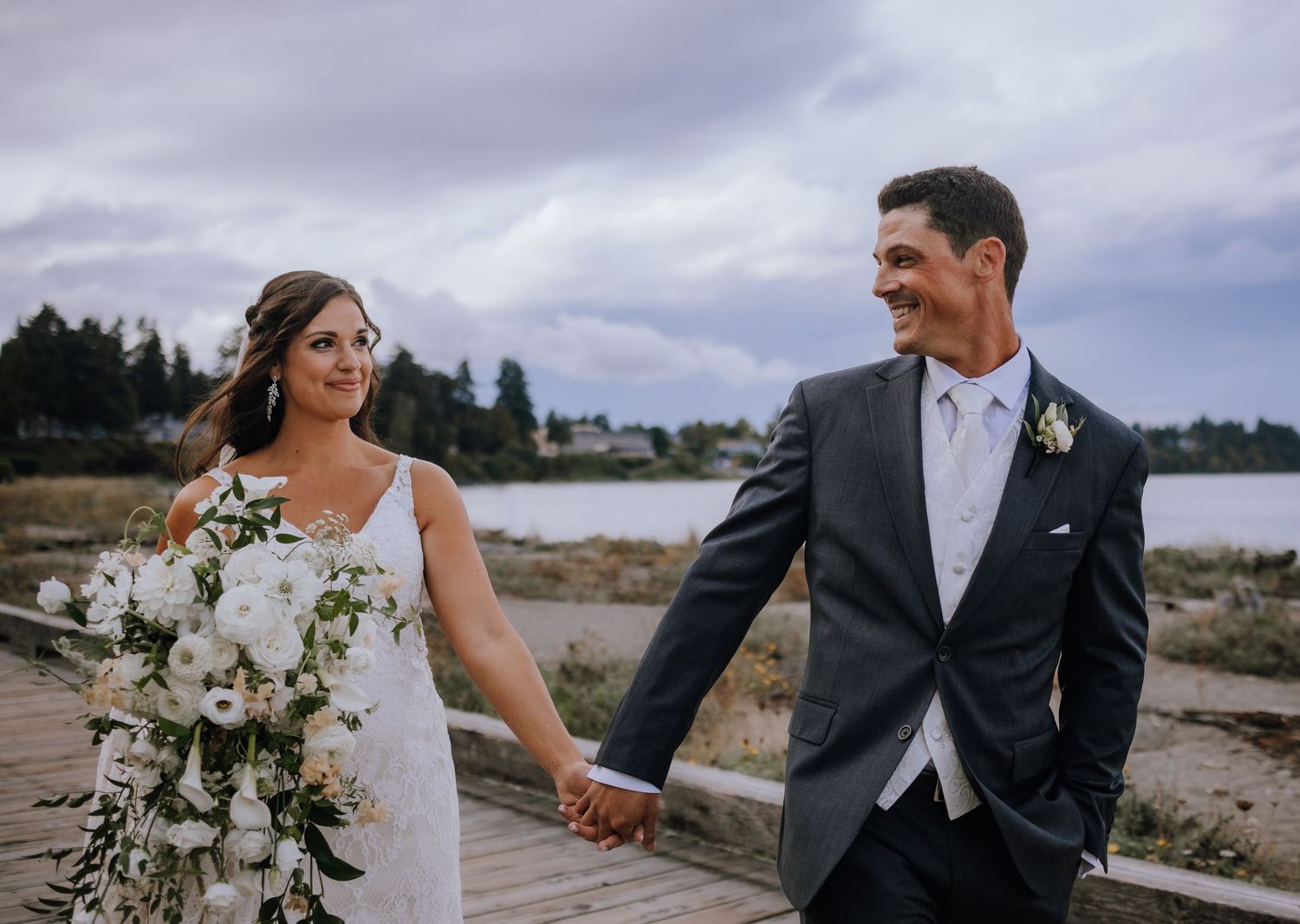 Newlywed couple shares romantic moments on a cloudy day against dramatic mountain landscape.