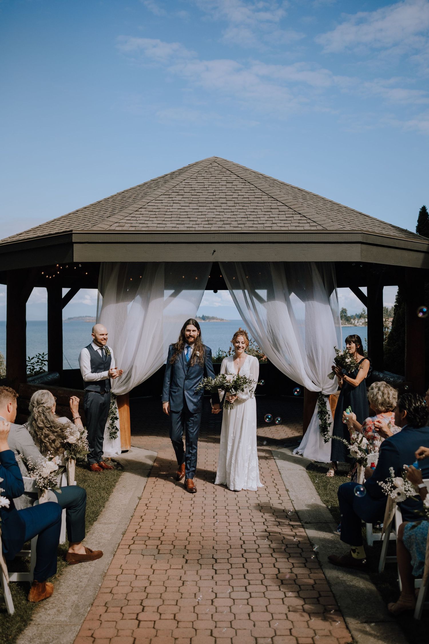 Outdoor wedding ceremony setup with white curtains and covered pavilion on a sunny day with blue skies at Tigh-Na-Mara Resort in Parksville