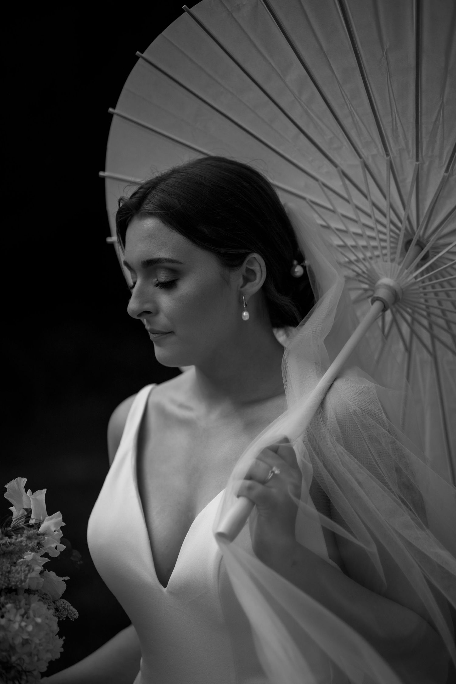 Artistic black and white bridal portrait series with white parasol and elegant V-neck dress showing graceful poses.