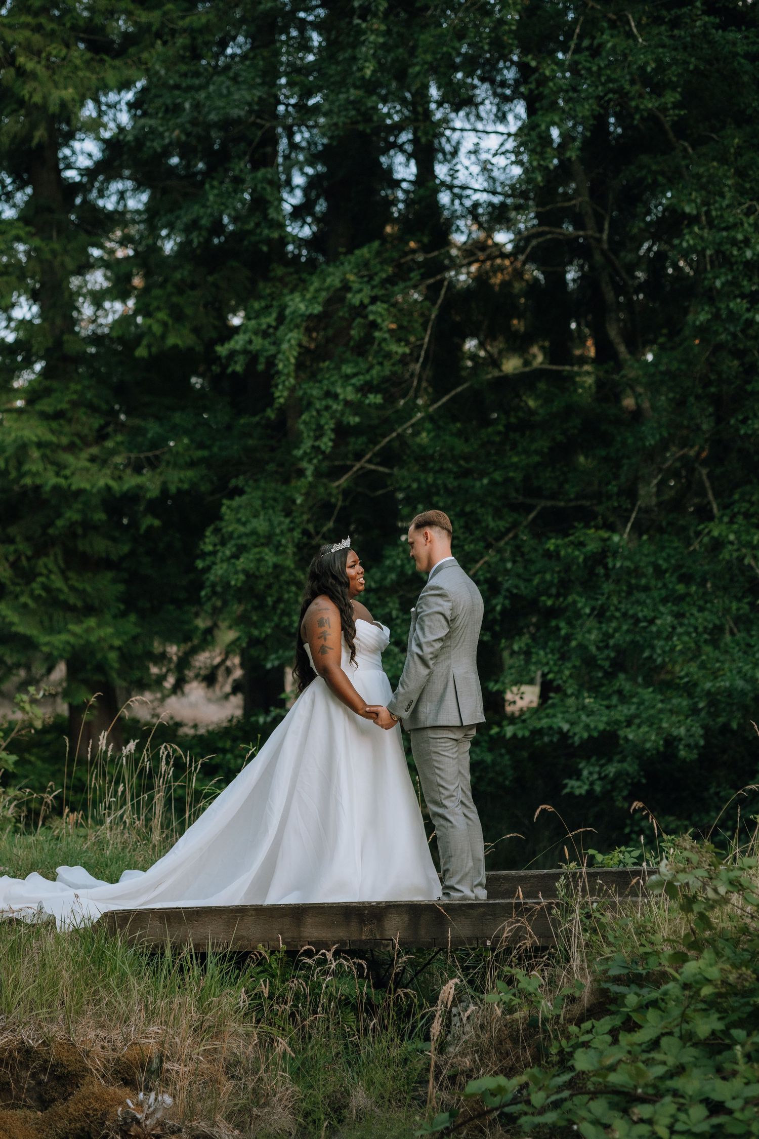 A couple shares a romantic moment in their wedding attire on a wooden walkway at Olympic View Golf Course in Victoria BC