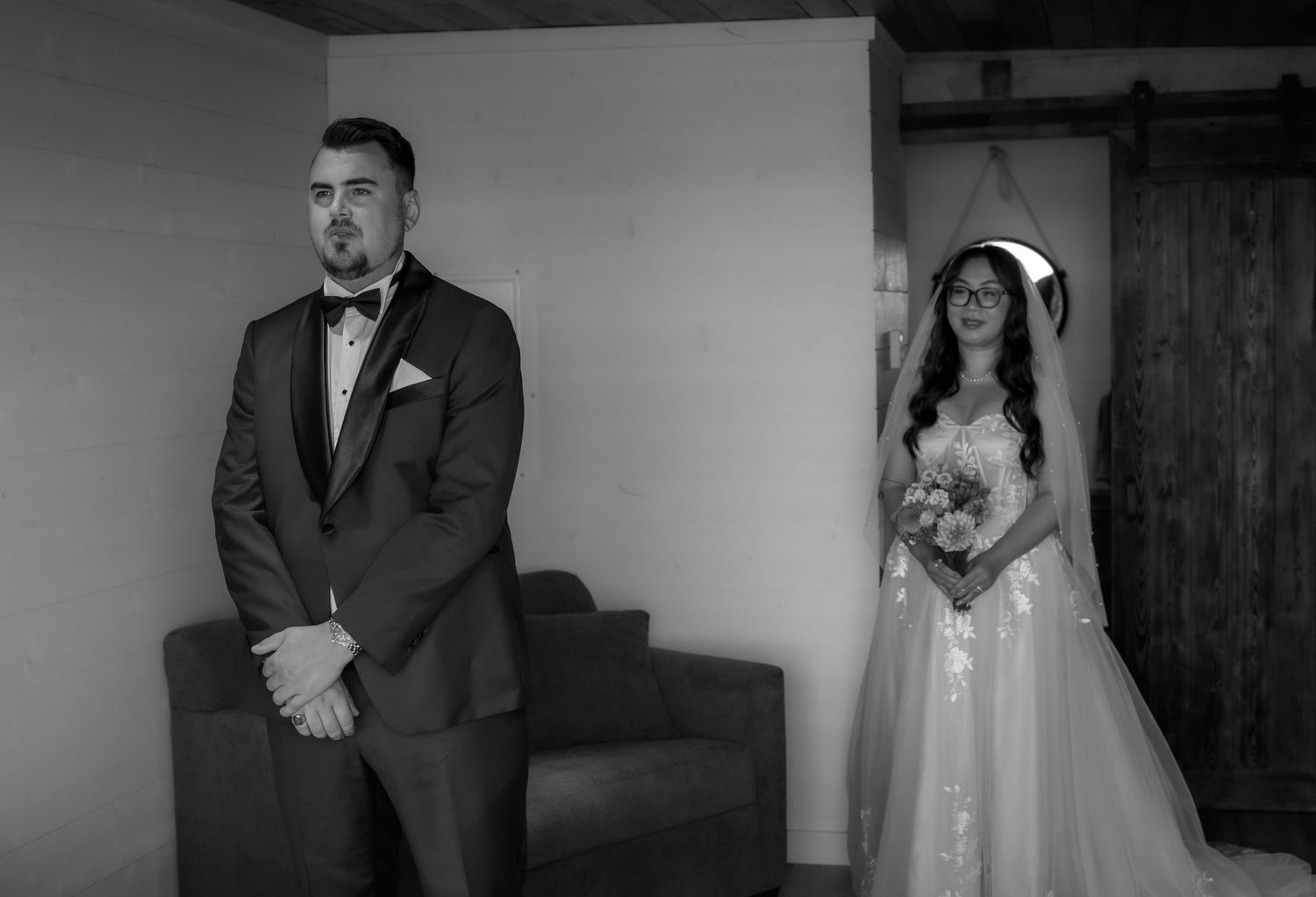 A couple during their first look moment at a rustic wedding venue, captured in black and white.