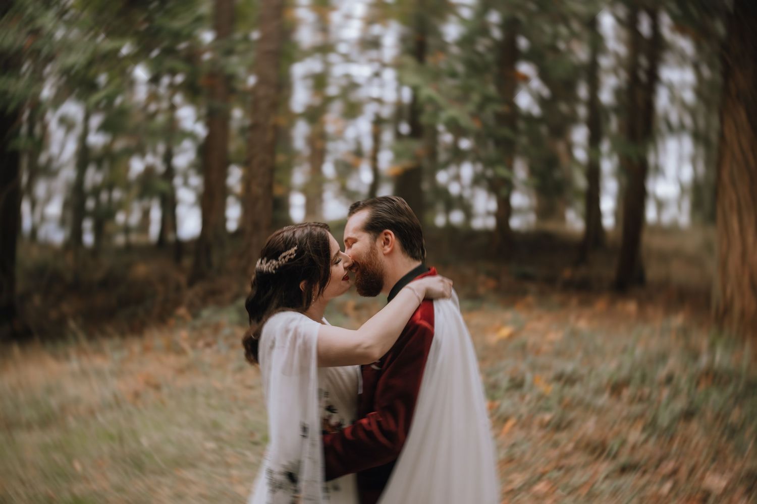 Couple sharing romantic moments in a forest setting during their wedding celebration.