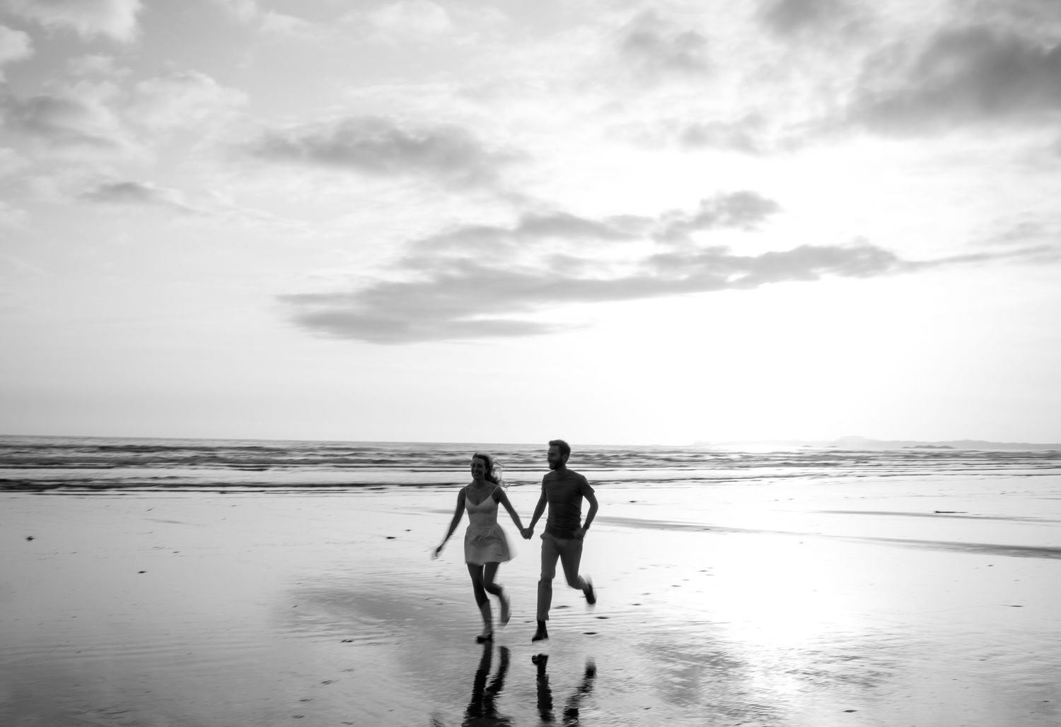 Silhouettes of people walking together along a misty beach at sunset, creating a romantic seaside atmosphere in Tofino, BC