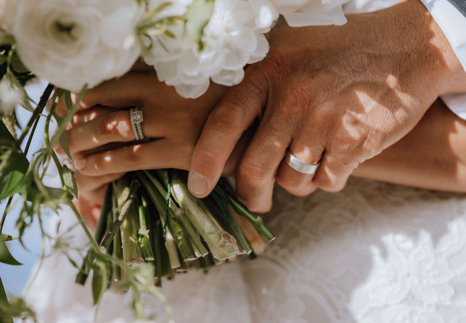 A series of hands carefully arranging white roses and greenery into a floral bouquet.