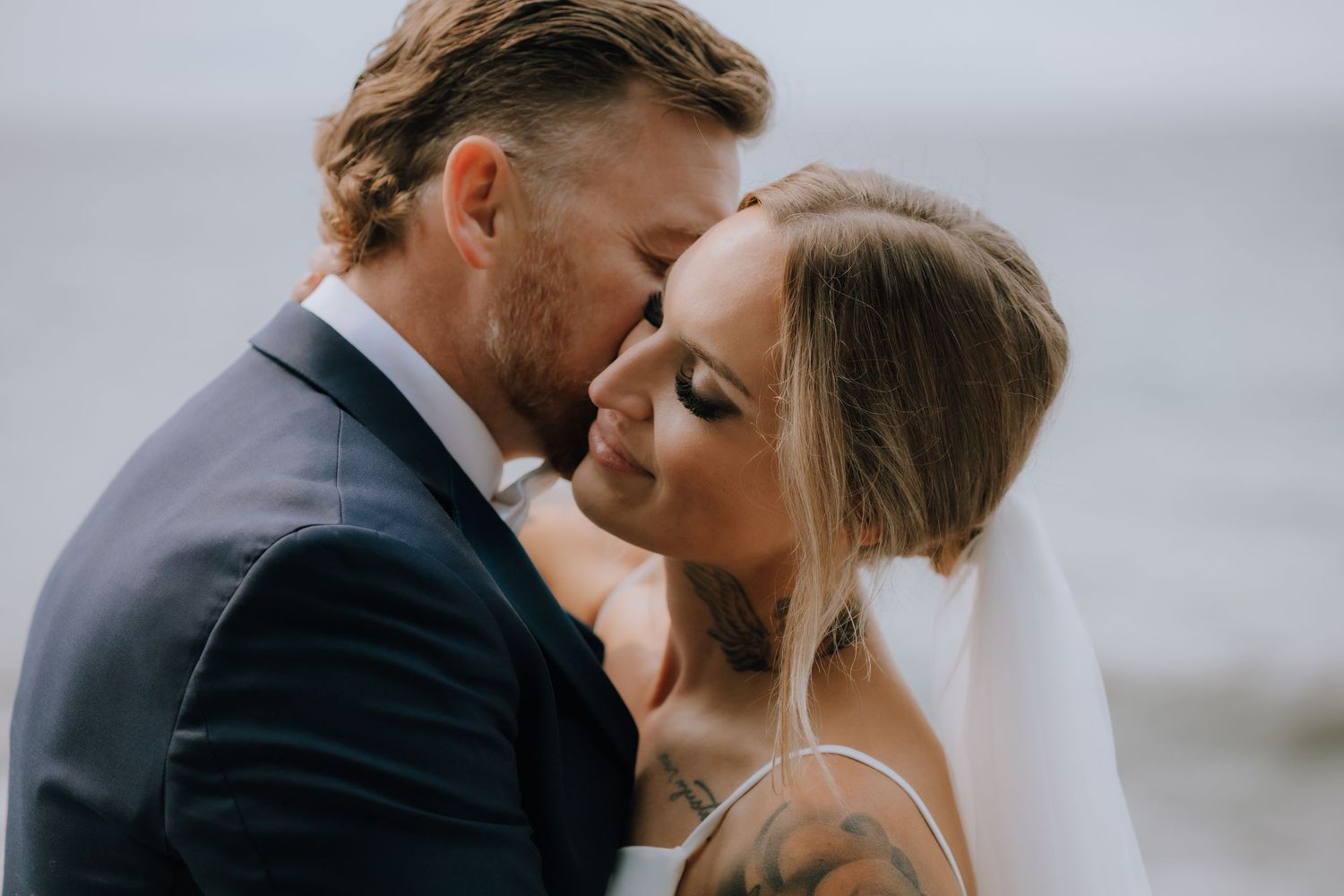 A romantic couple shares an intimate moment at their wedding by the ocean.